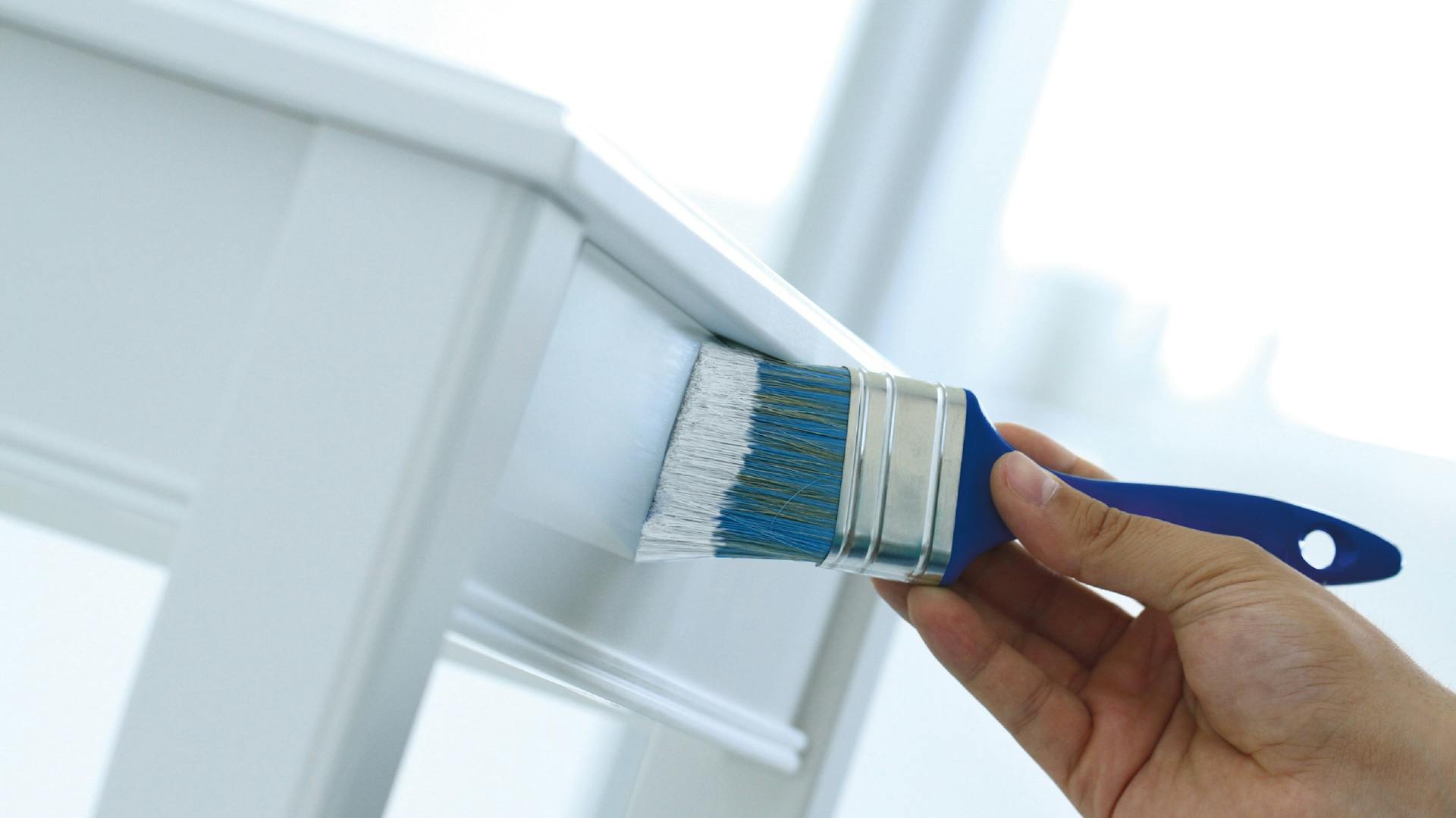 Egy férfi széket fest fehérre ecsettel