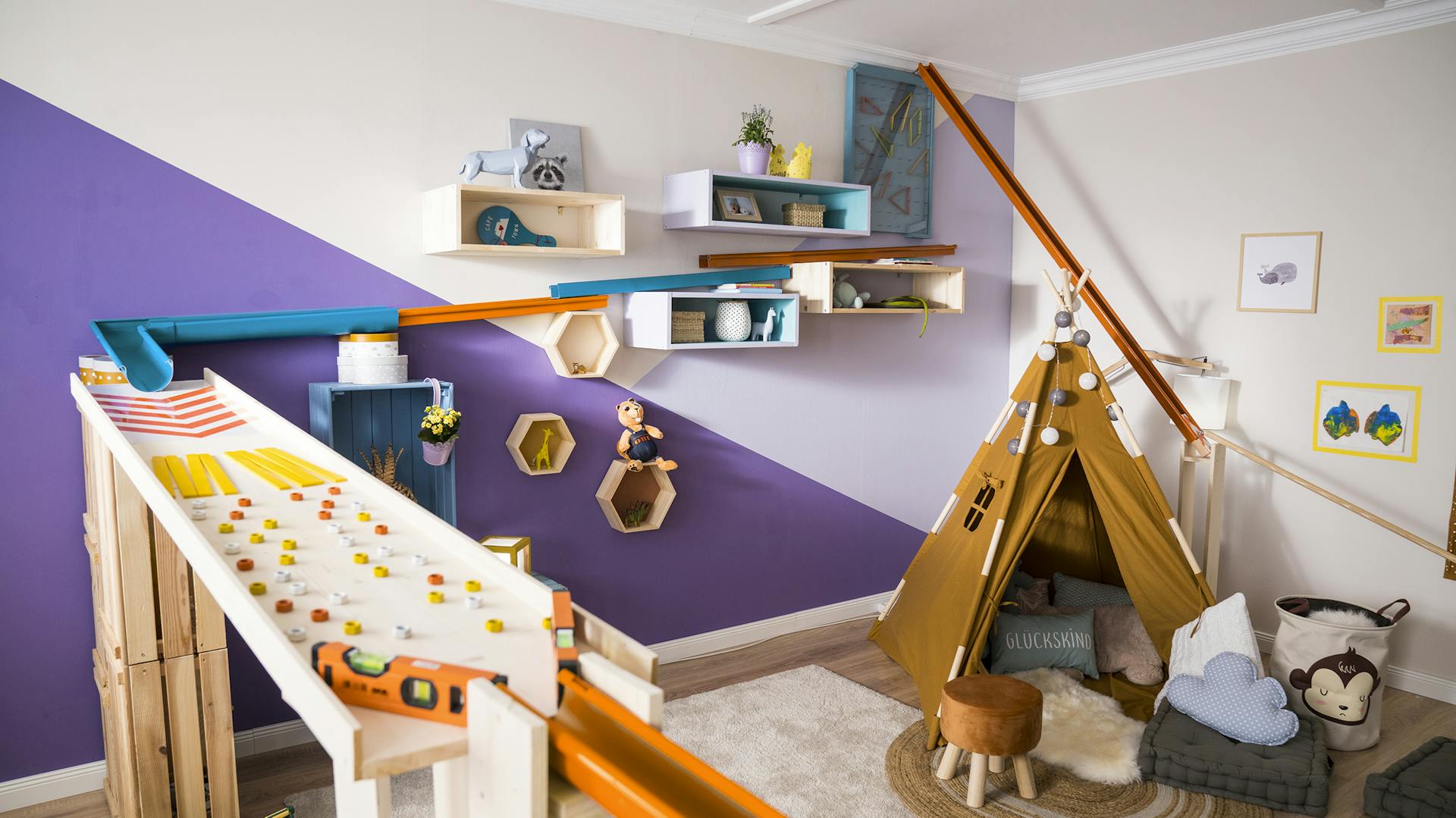 Über die bunte Wand eines Kinderzimmers verlaufen die Bahnen der DIY-Murmelbahn.