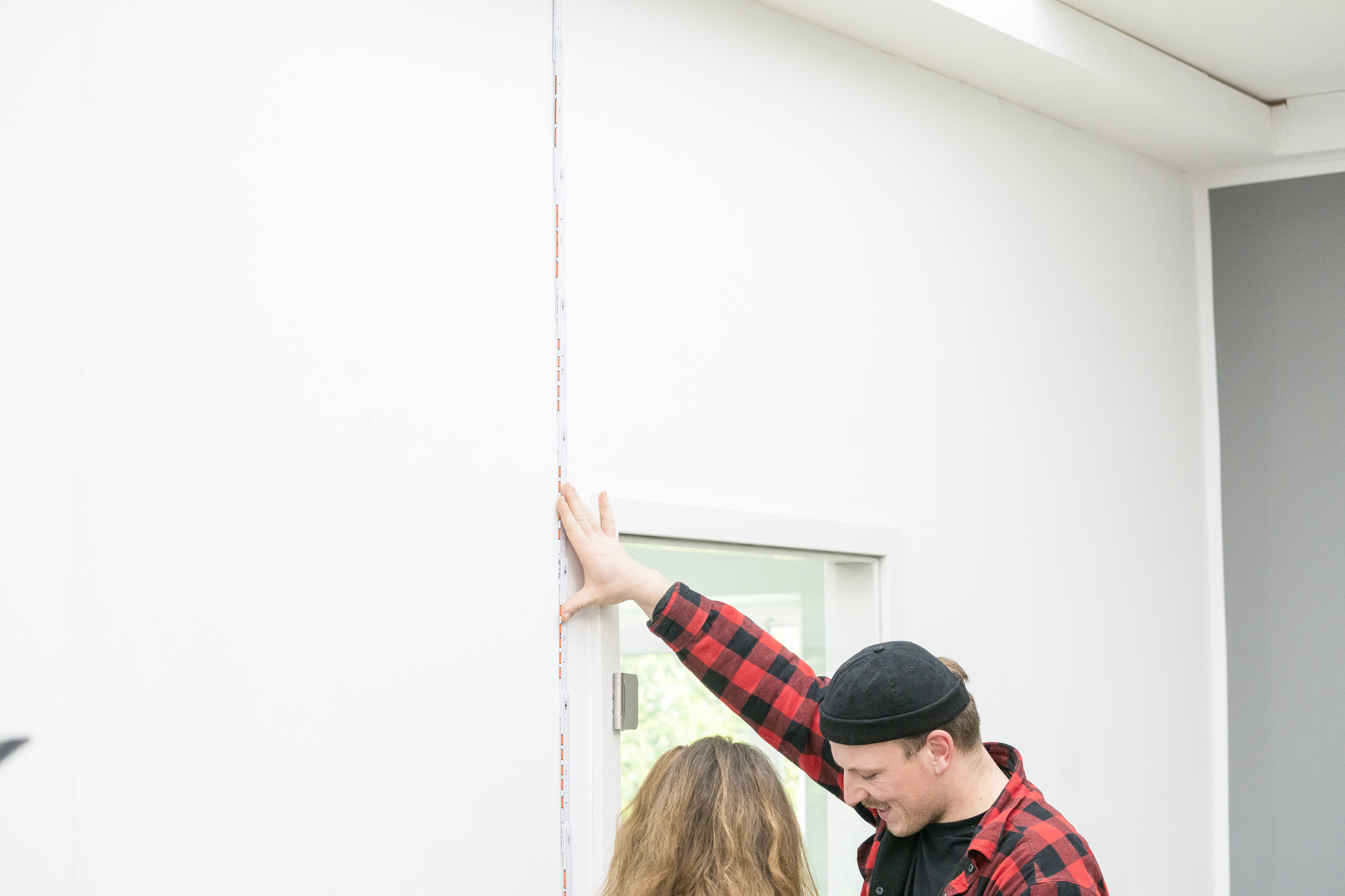 Zwei Personen messen eine Wand aus.