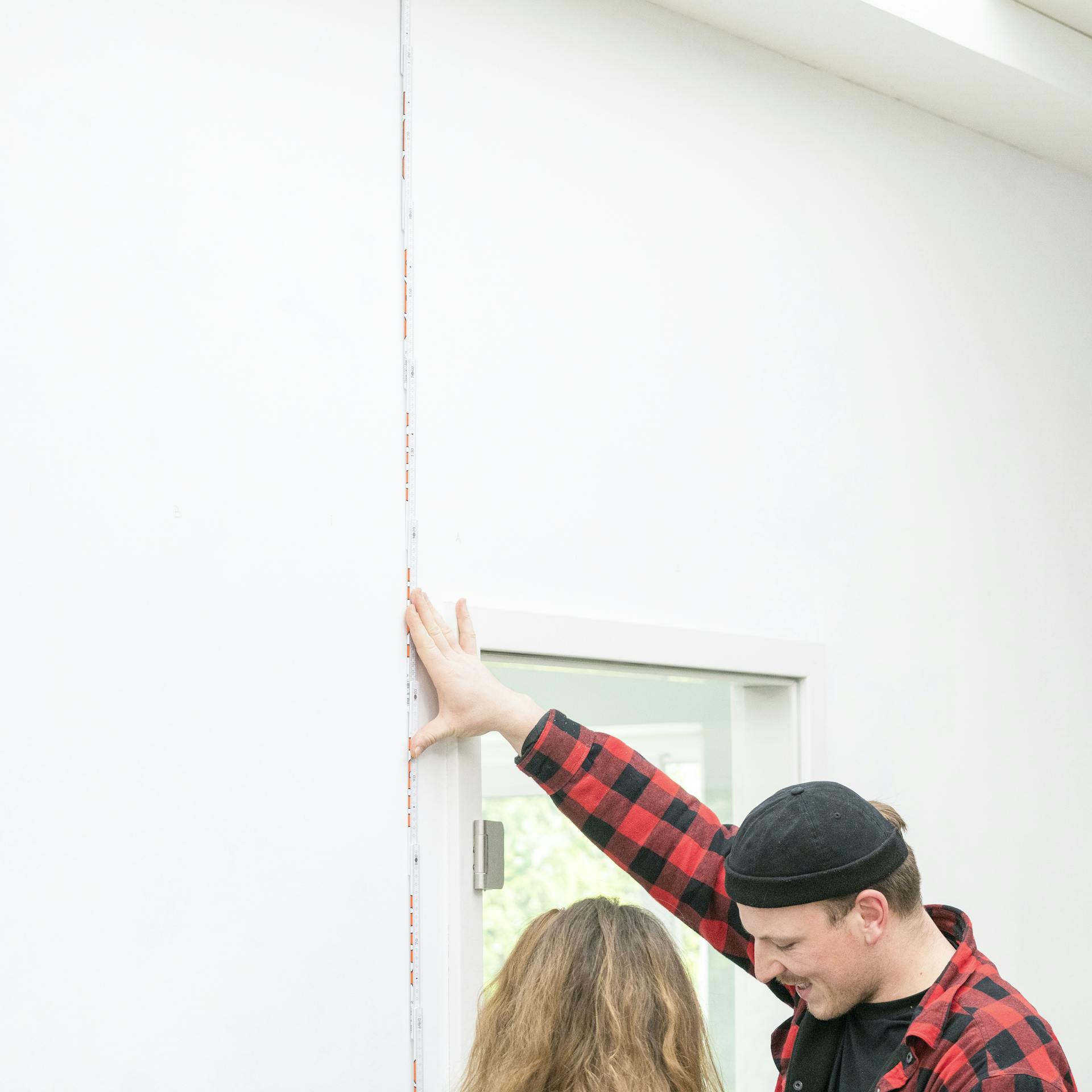 Zwei Personen messen eine Wand aus.