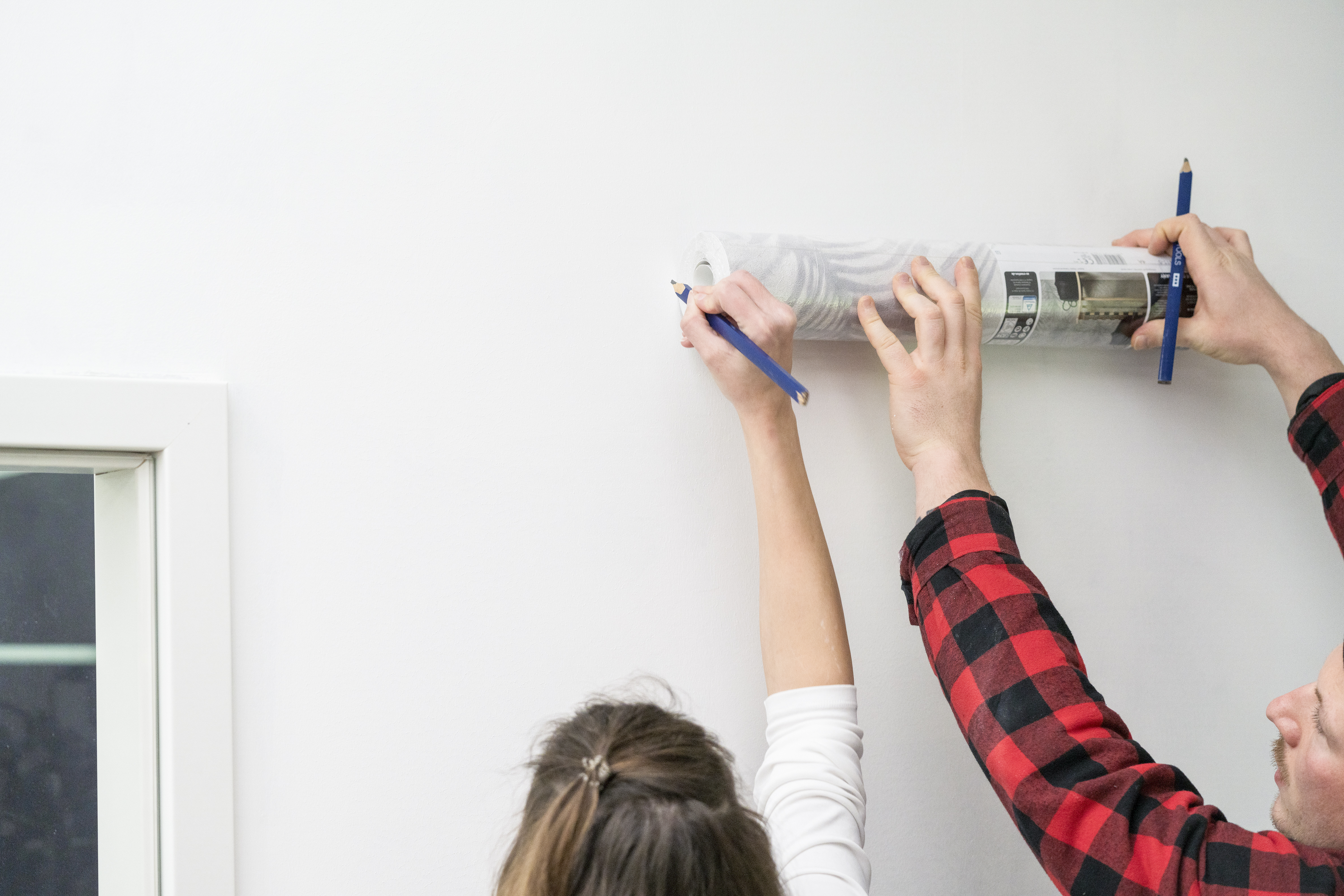Zwei Personen messen eine Wand aus.