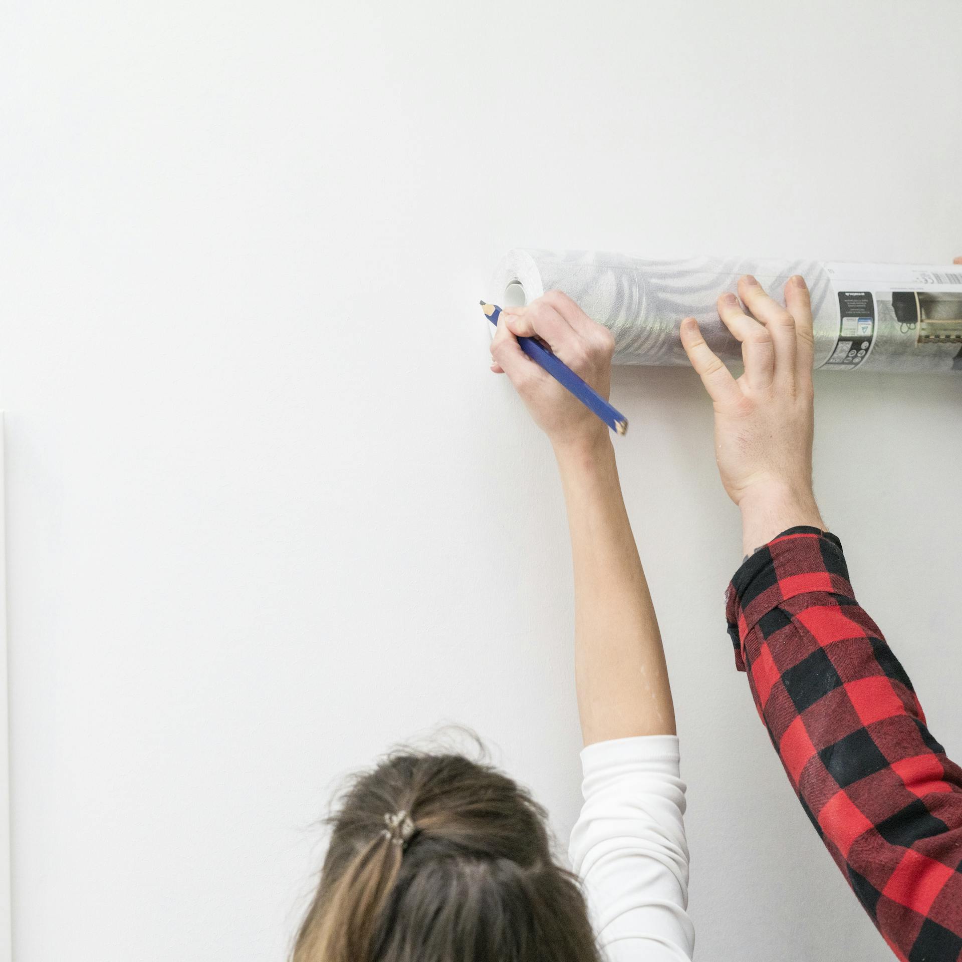 Zwei Personen messen eine Wand aus.