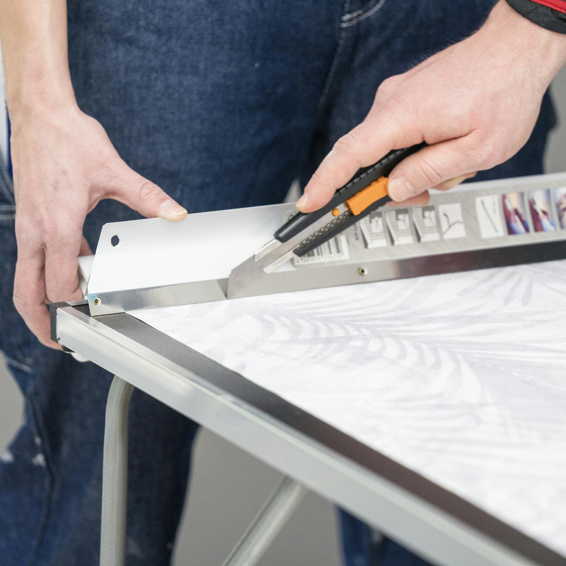 Jemand schneidet Tapete mit einem Cutter zu.