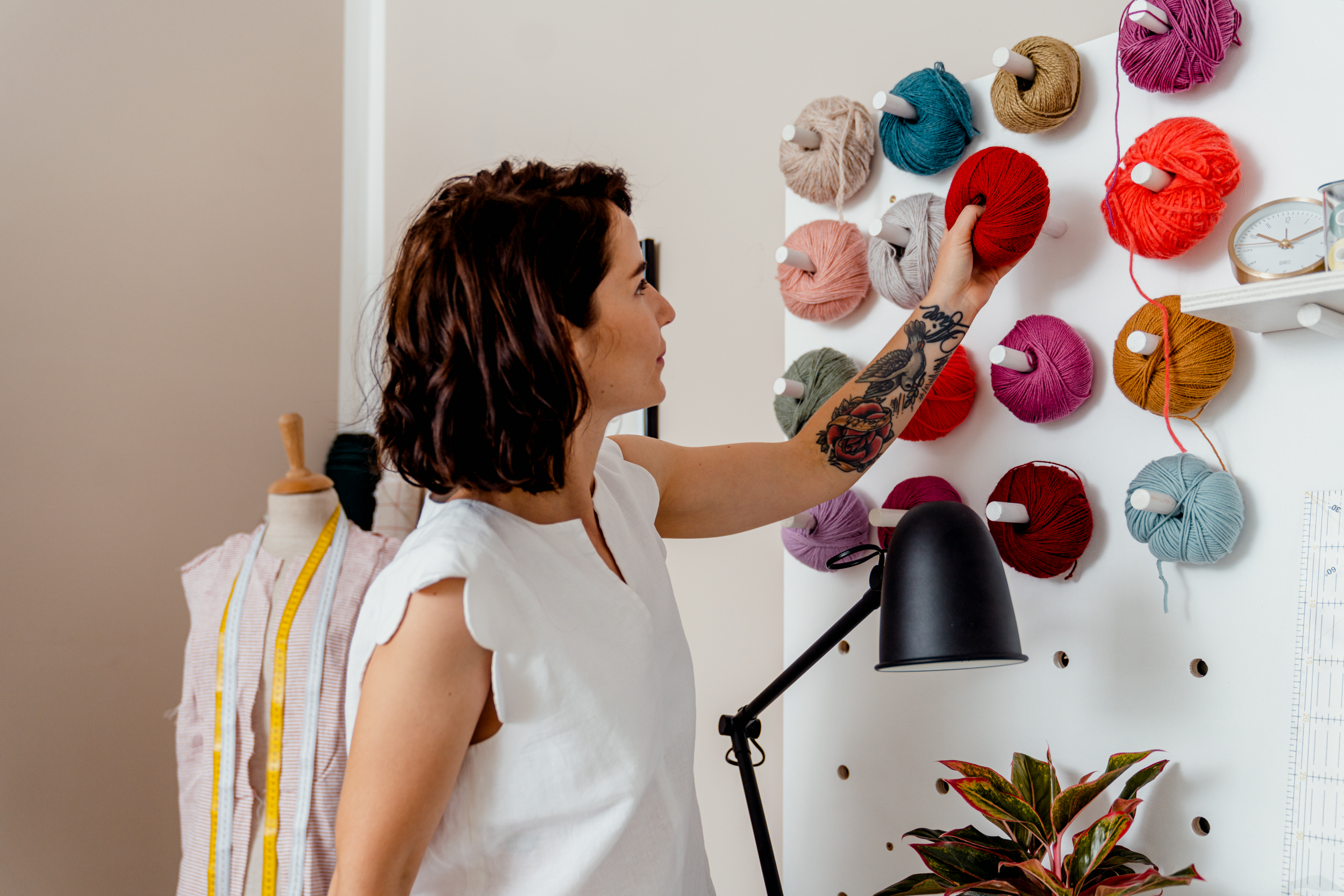 Frau steckt ein Wollknäuel auf ihr Pegboard.