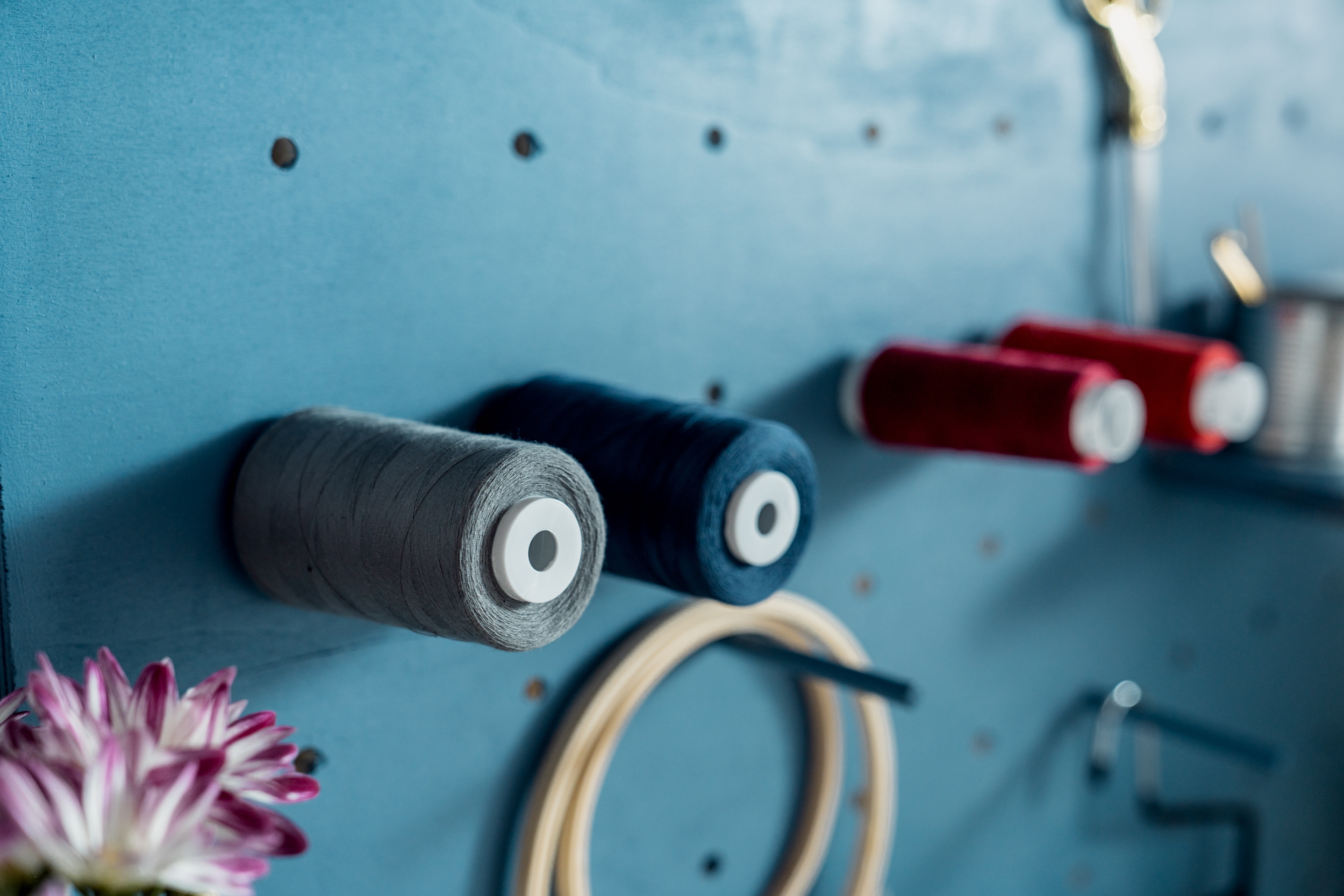 Blaues Pegboard mit aufgesteckten Garnrollen 