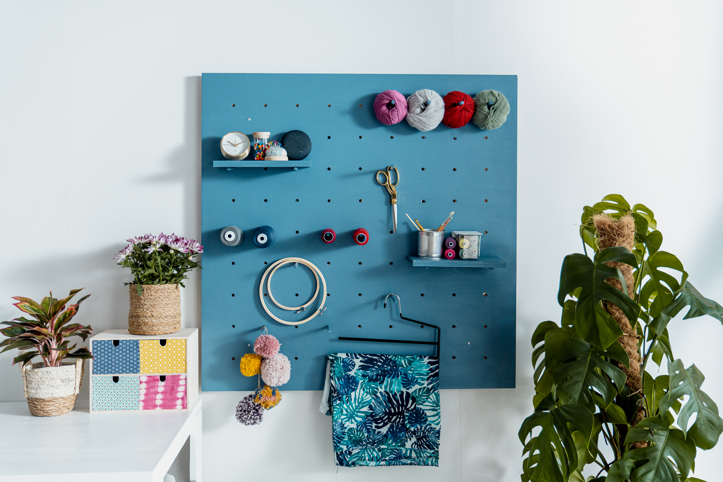 Pegboard in blau mit Nähutensilien daran