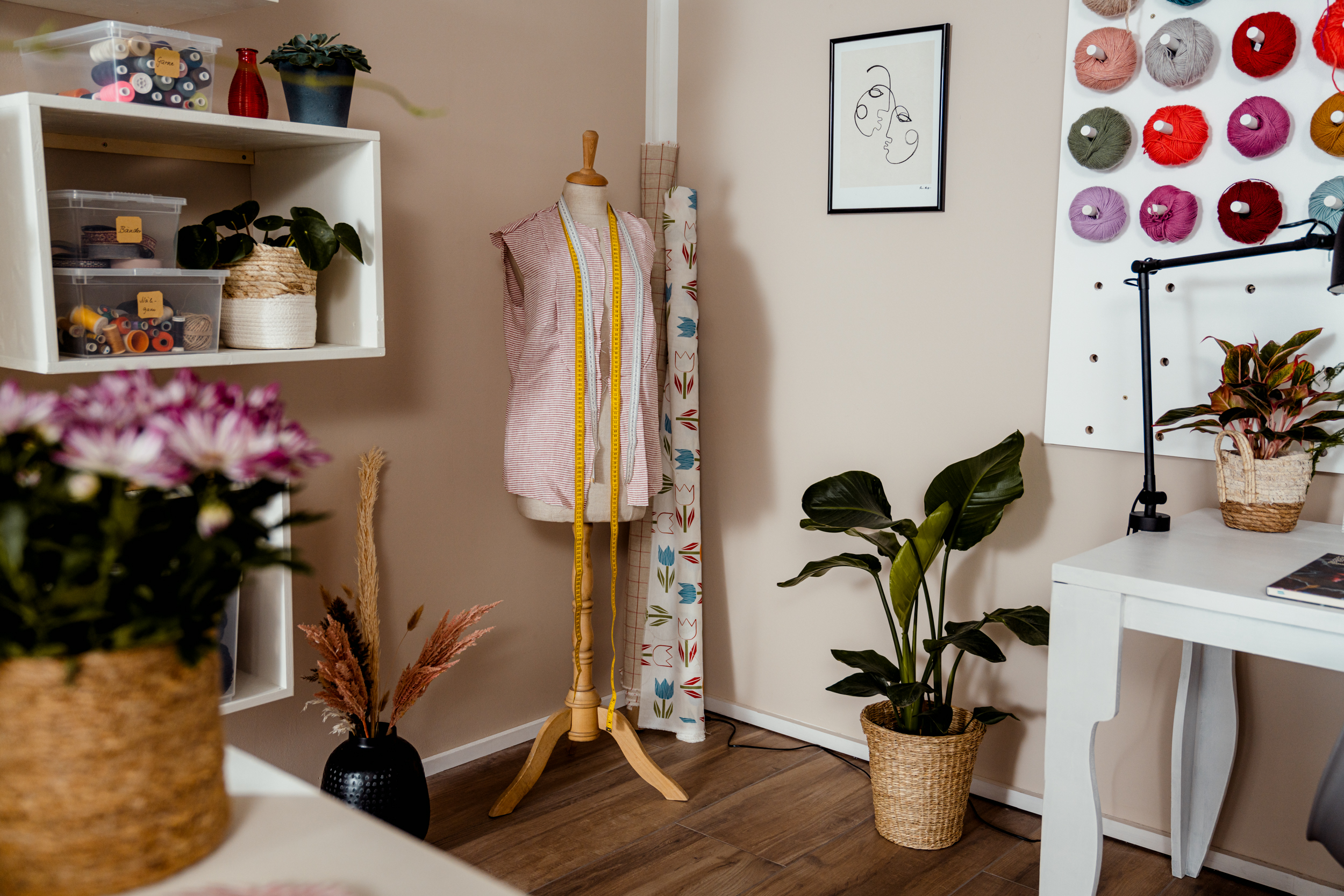 Aufgerollte Stoffe stehen im Nähzimmer neben einer Schneiderpuppe
