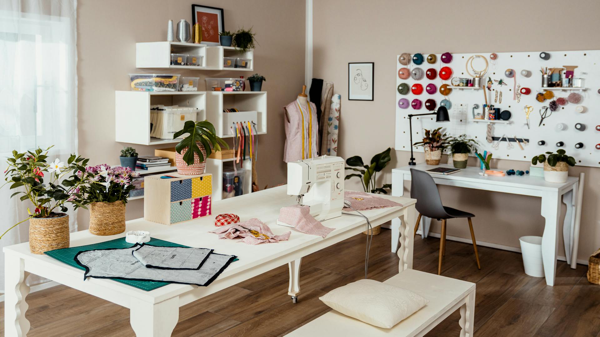 Fertig eingerichtetes Nähzimmer mit Tisch, Regalen und Pegboard.