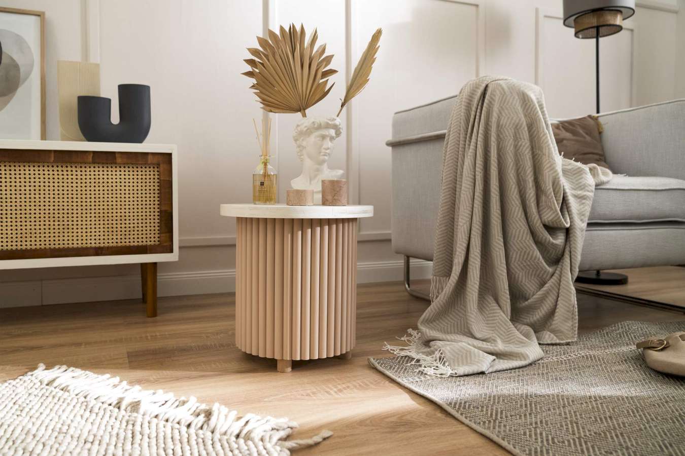 Ein Beistelltisch mit Lamellen zwischen einem Regal und einer Couch in einem Wohnzimmer