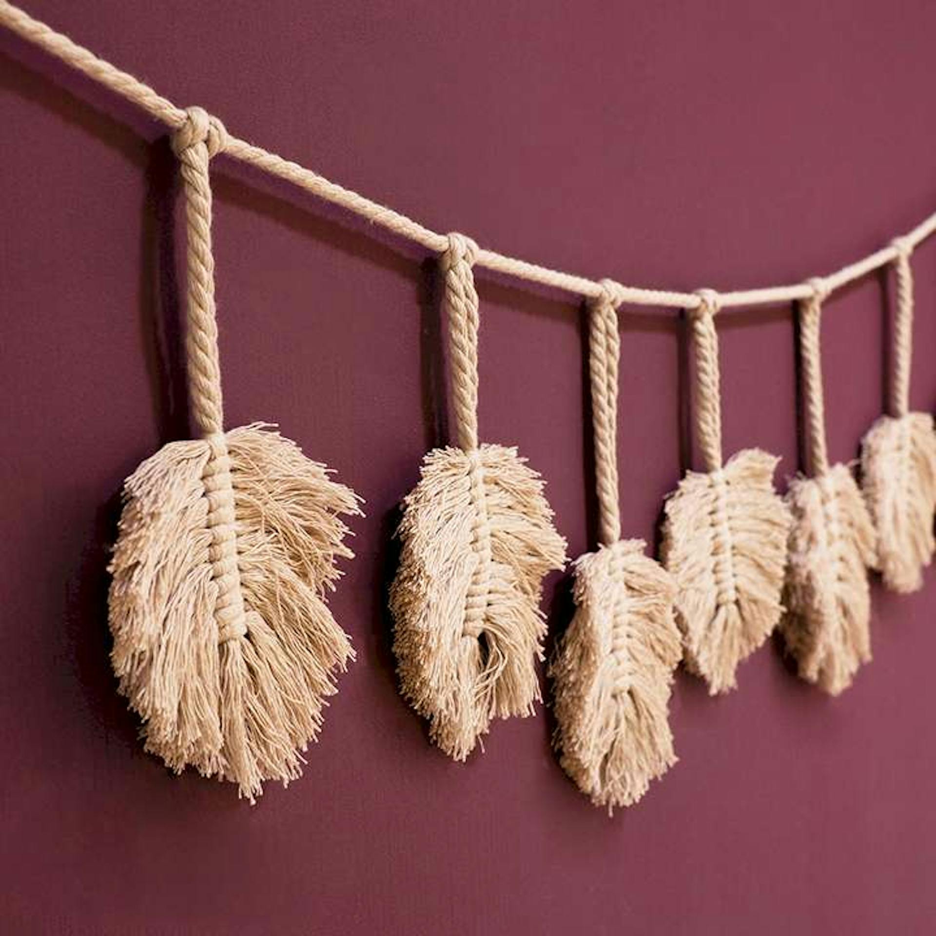 DIY Seil mit geflochtenen Federn an der Wand.