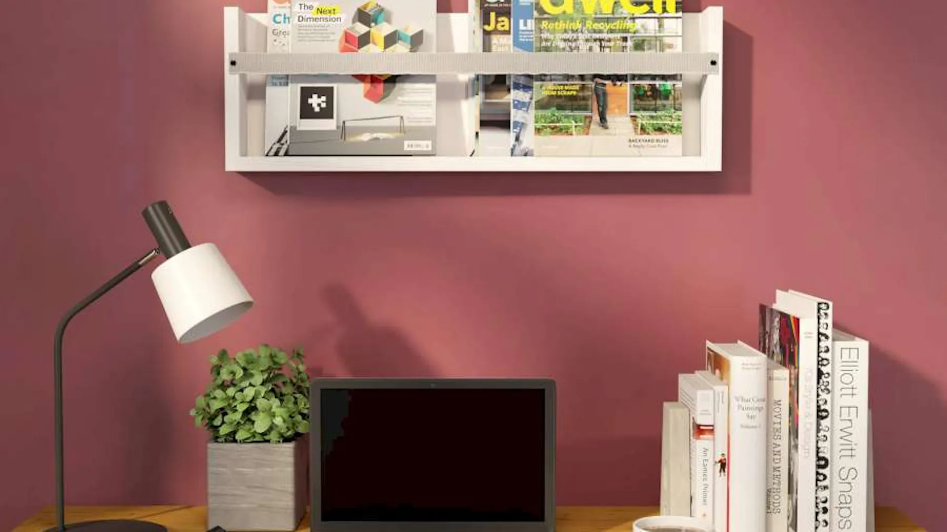 Ein Magazinregal hängt an einer roten Wand über einem Schreibtisch.