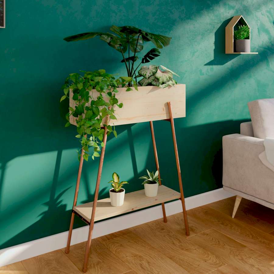 Vor einer grünen Wand steht ein Pflanzregal mit Kupferfüßen neben einem Sofa. 