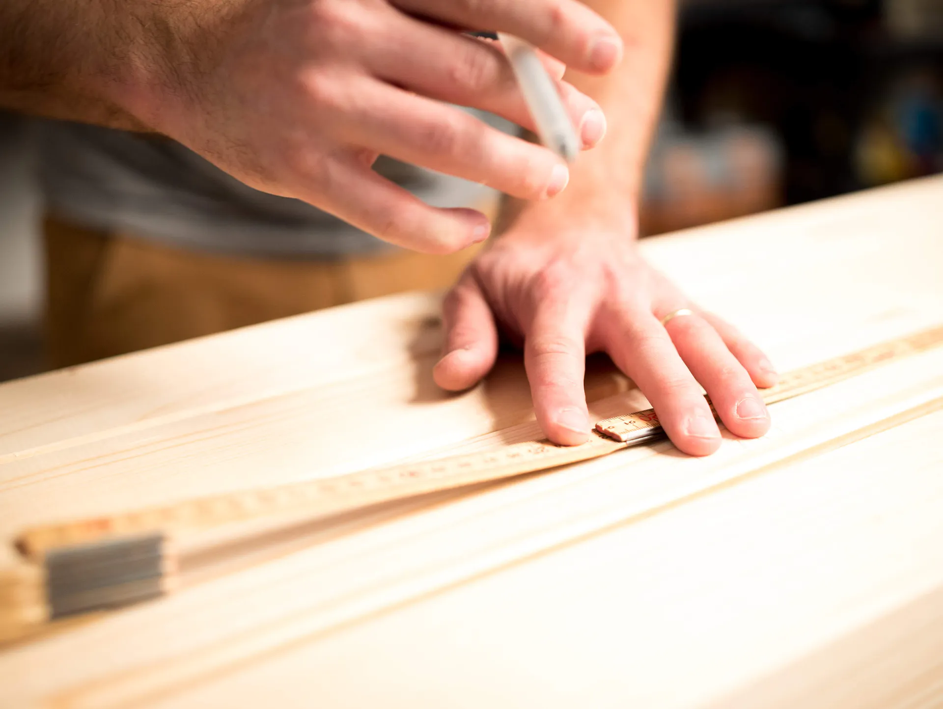 Heimwerker misst Holz mit Lineal aus.