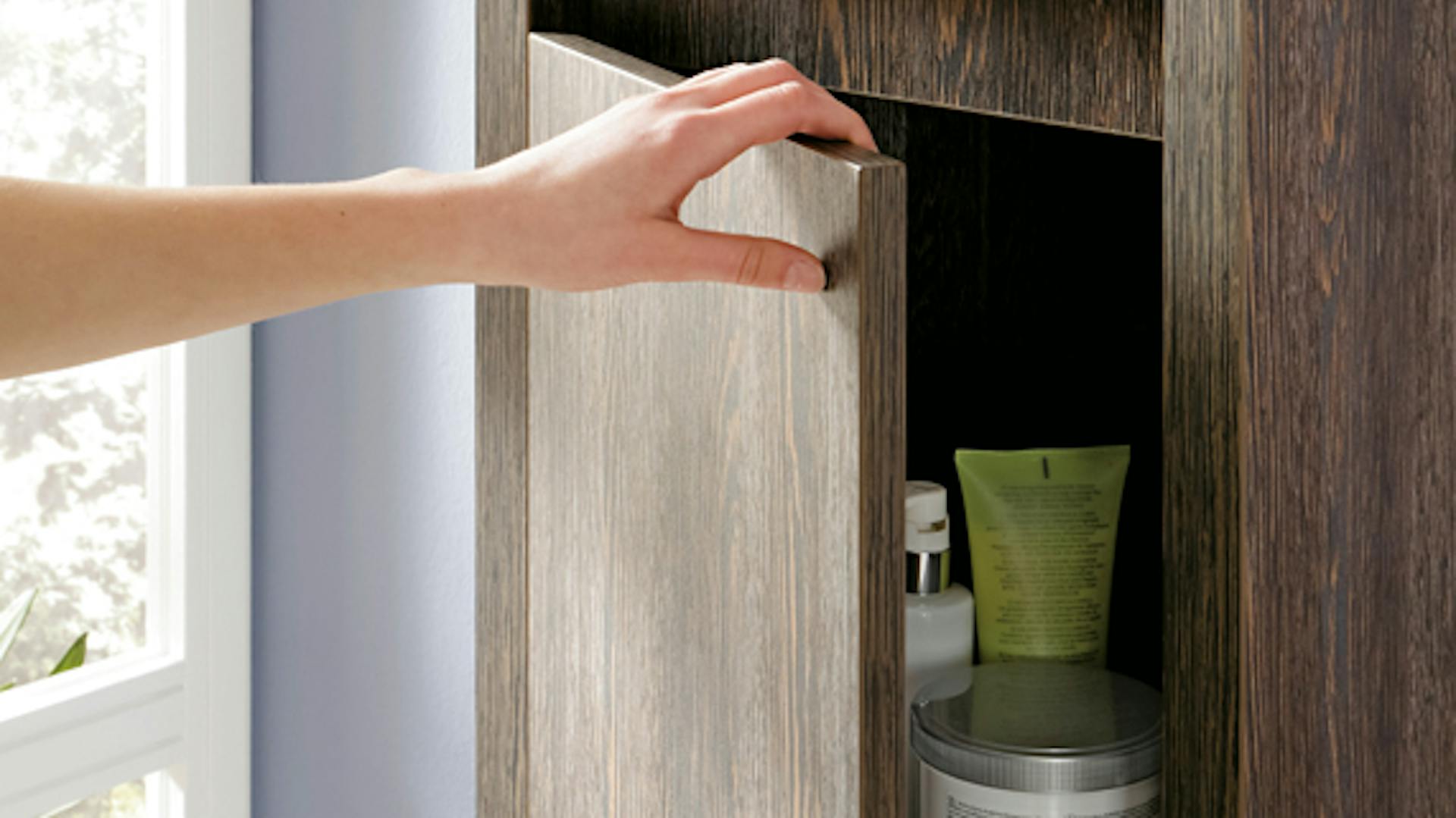 Jemand öffnet einen Badezimmerschrank.