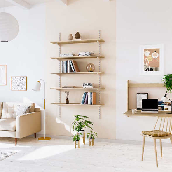 Zwischen einem hellen Sofa und einem Schreibtisch hängt ein Regal, hinter dem sich eine beige Farbfläche befindet.
