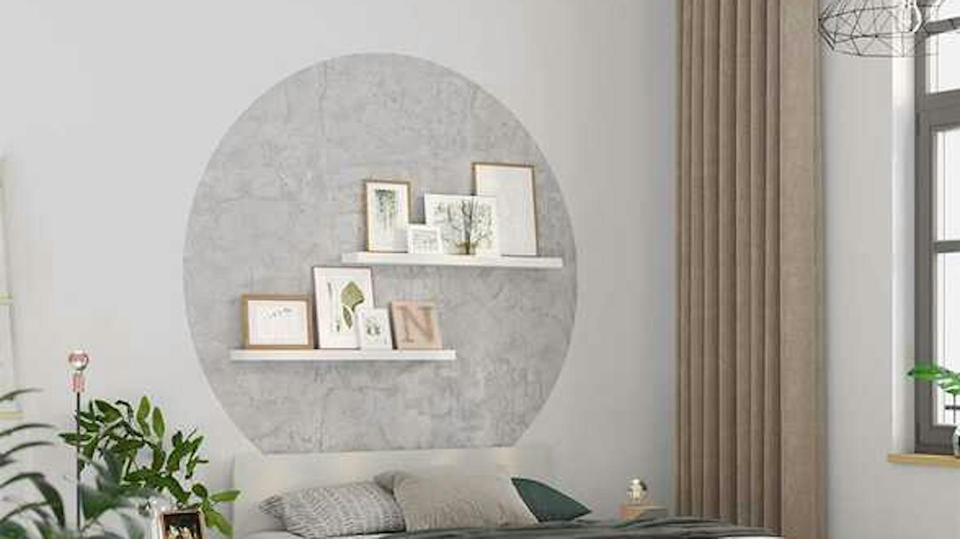 An der Wand hinter einem Bett befindet sich ein grauer Kreis aus Tapete. An dieser Stelle sind zwei Bilderleisten platziert worden.