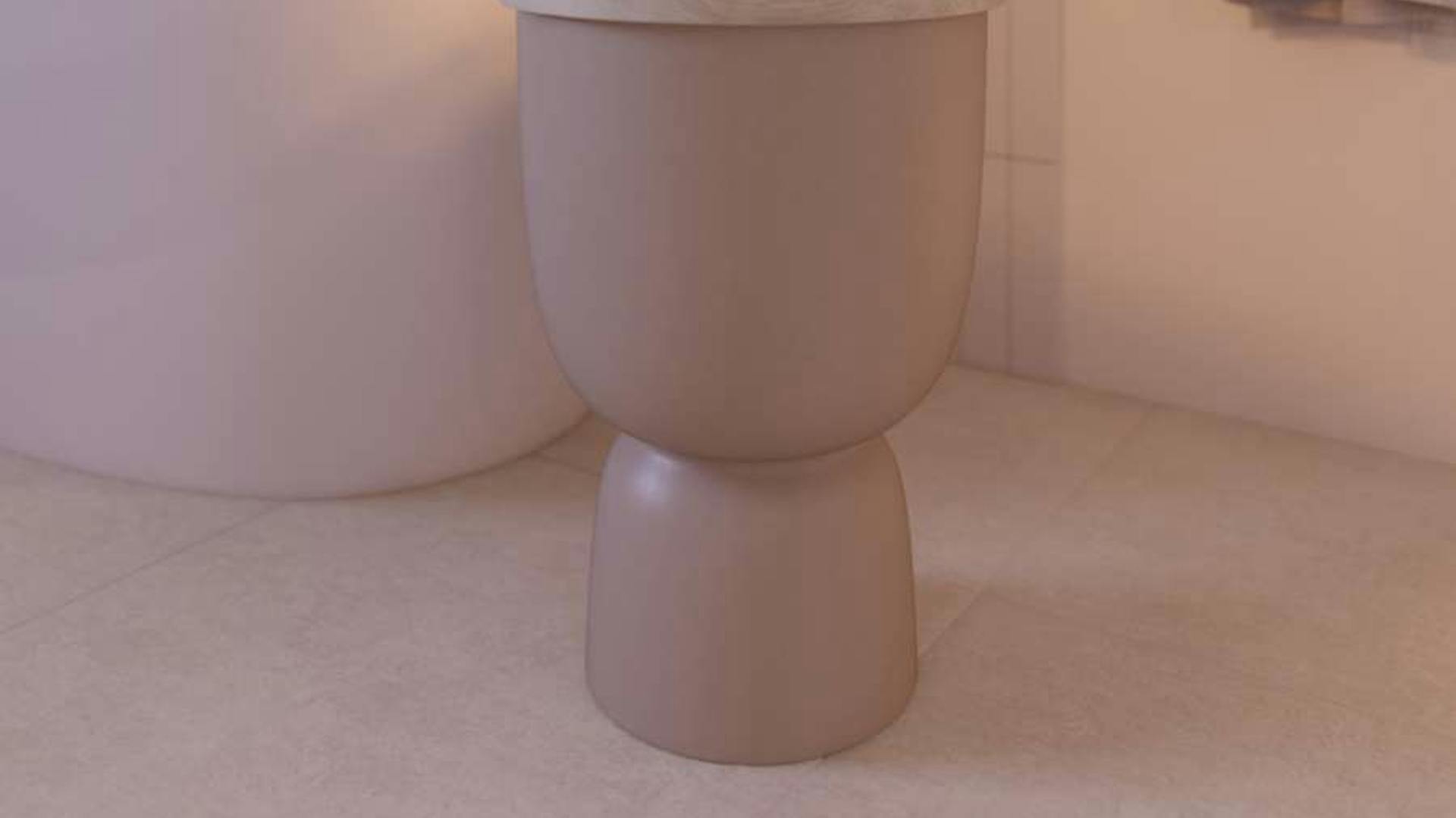 In einem Badezimmer steht ein runder Beistelltisch mit Stauraum vor der Badewanne.