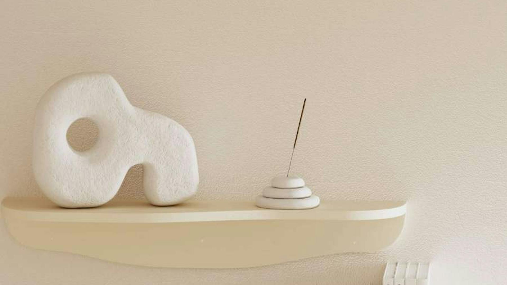 Auf einem Wandregal steht eine DIY-Skulptur in Steinoptik neben einem Räucherstäbchenhalter