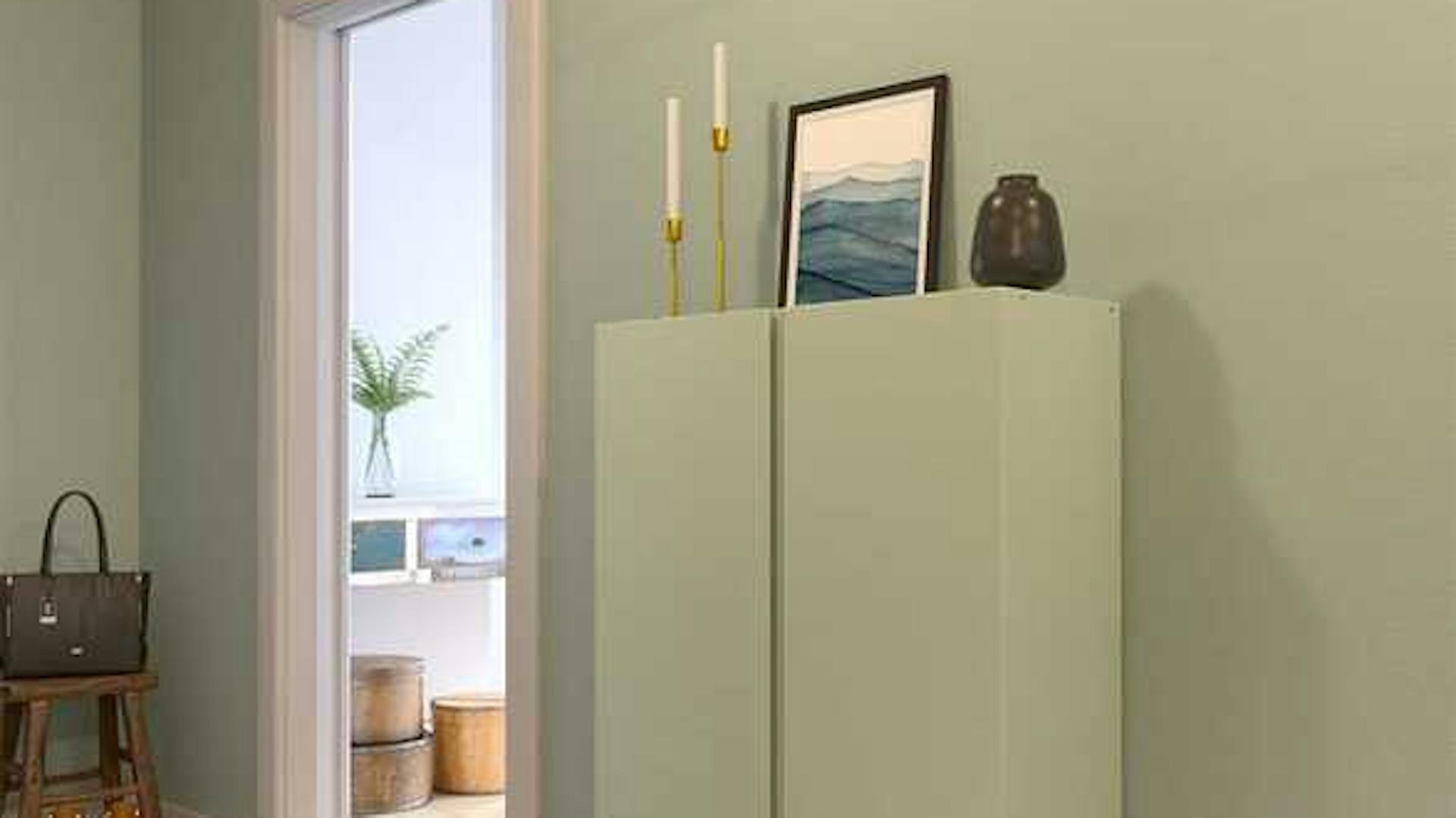 Ein Flur in einem salbeigrünem Farbton mit passend gestrichener Kommode.