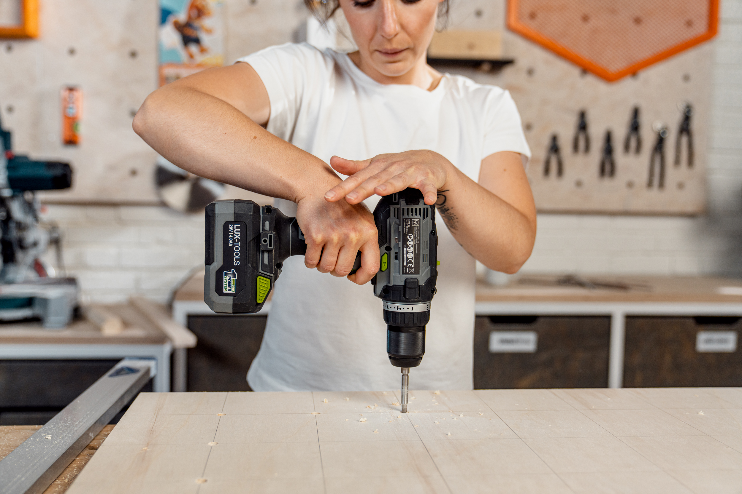 Person bohrt Löcher für Pegboard.