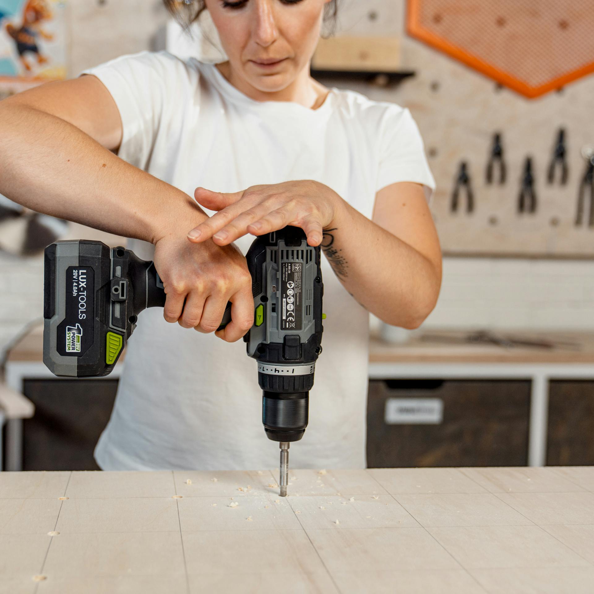 Person bohrt Löcher für Pegboard.