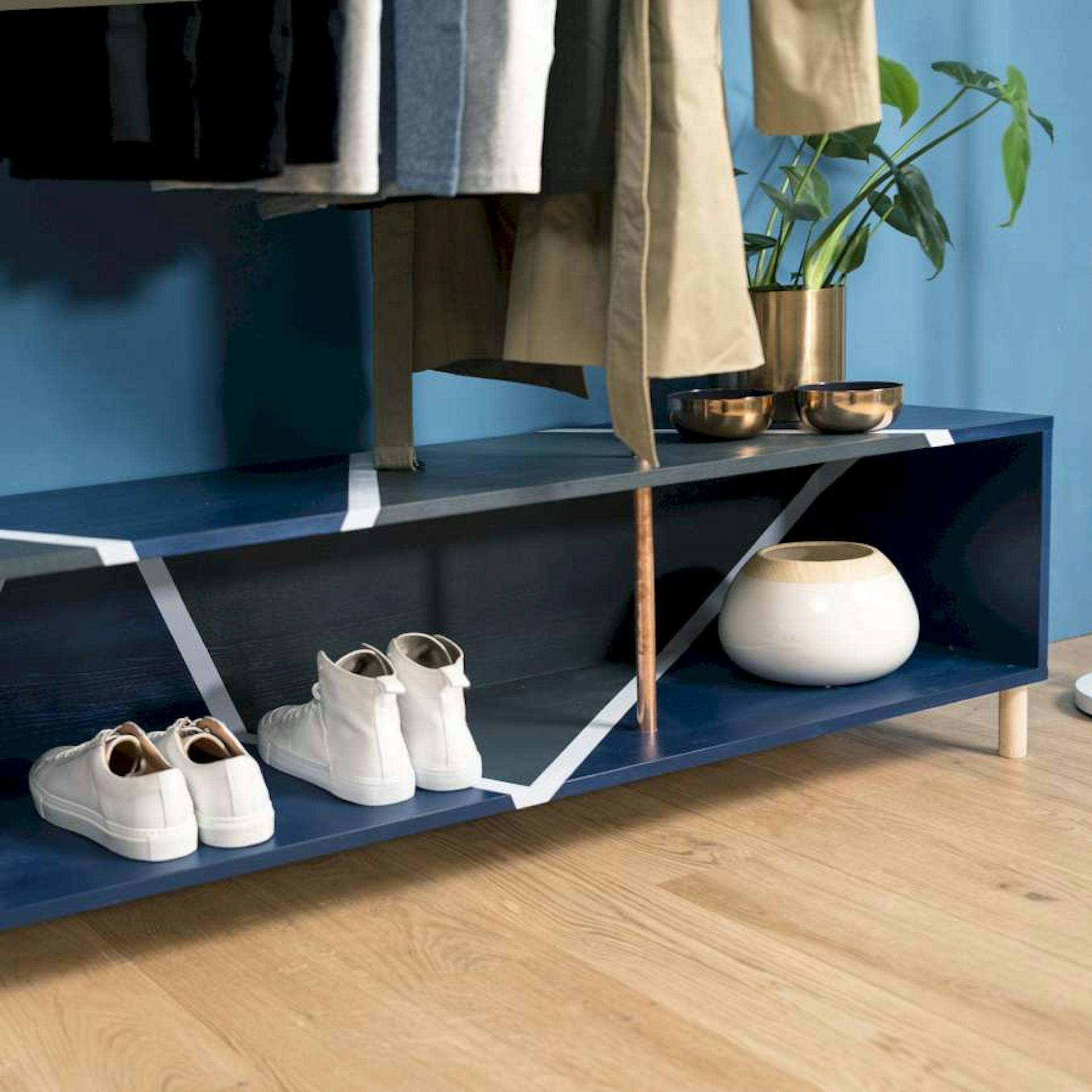 Ein blaues Schuhregal, in dem Dekoration und Schuhe stehen, wurde mit geometrischen Mustern verziert.