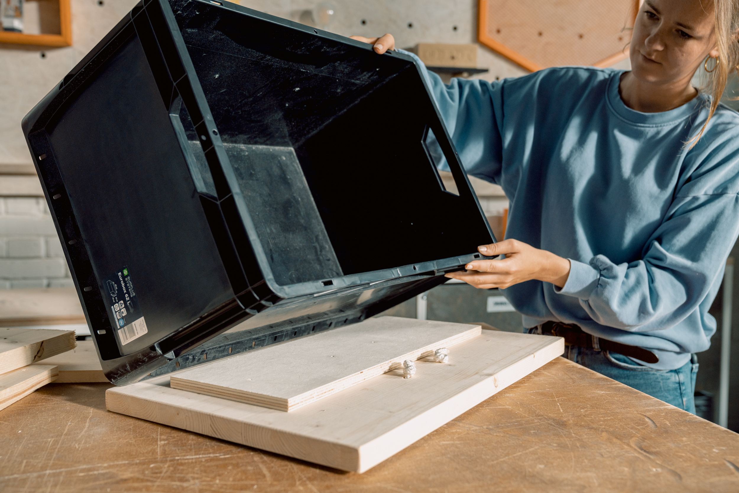 Eine Frau setzt eine Eurobox auf Holzplatten