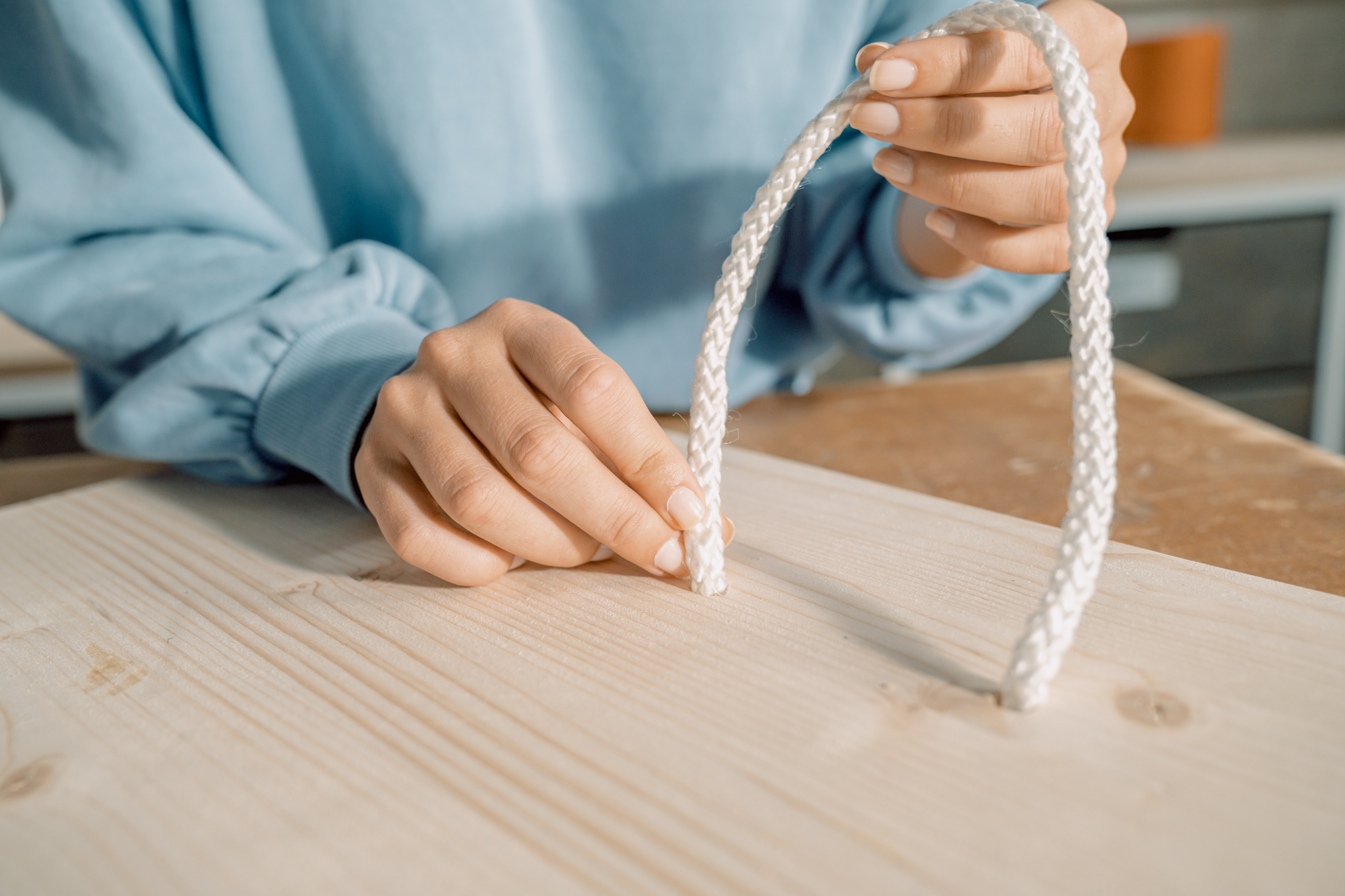Ein Seil wird in ein Holzbrett gefädelt