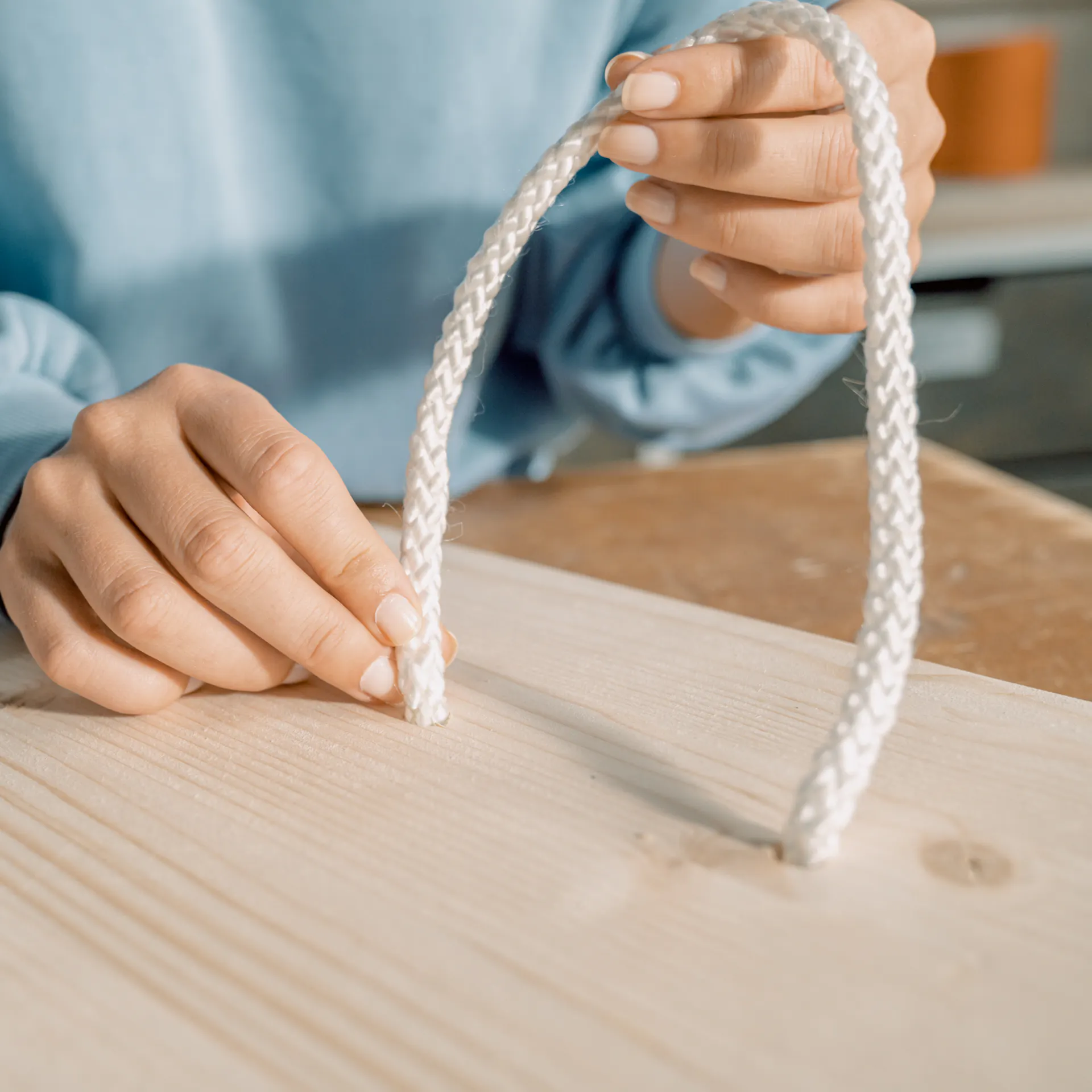 Ein Seil wird in ein Holzbrett gefädelt