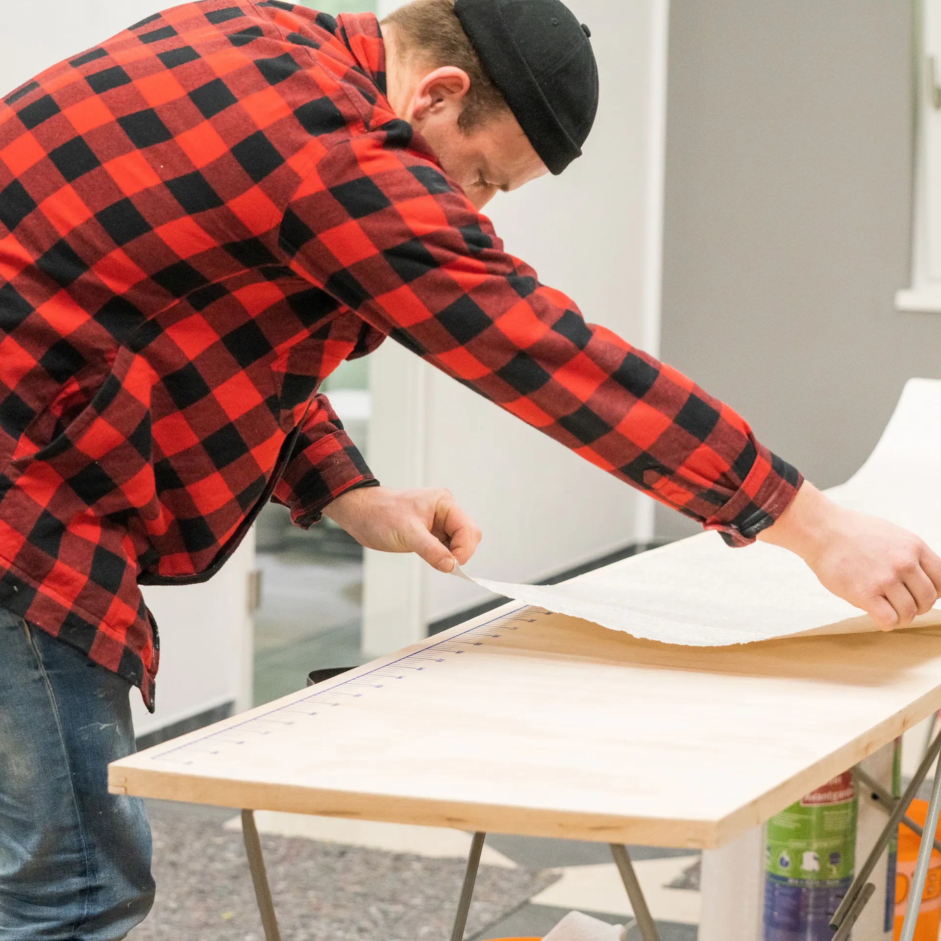 Kutil natahuje pás tapety přes tapetovací stůl.