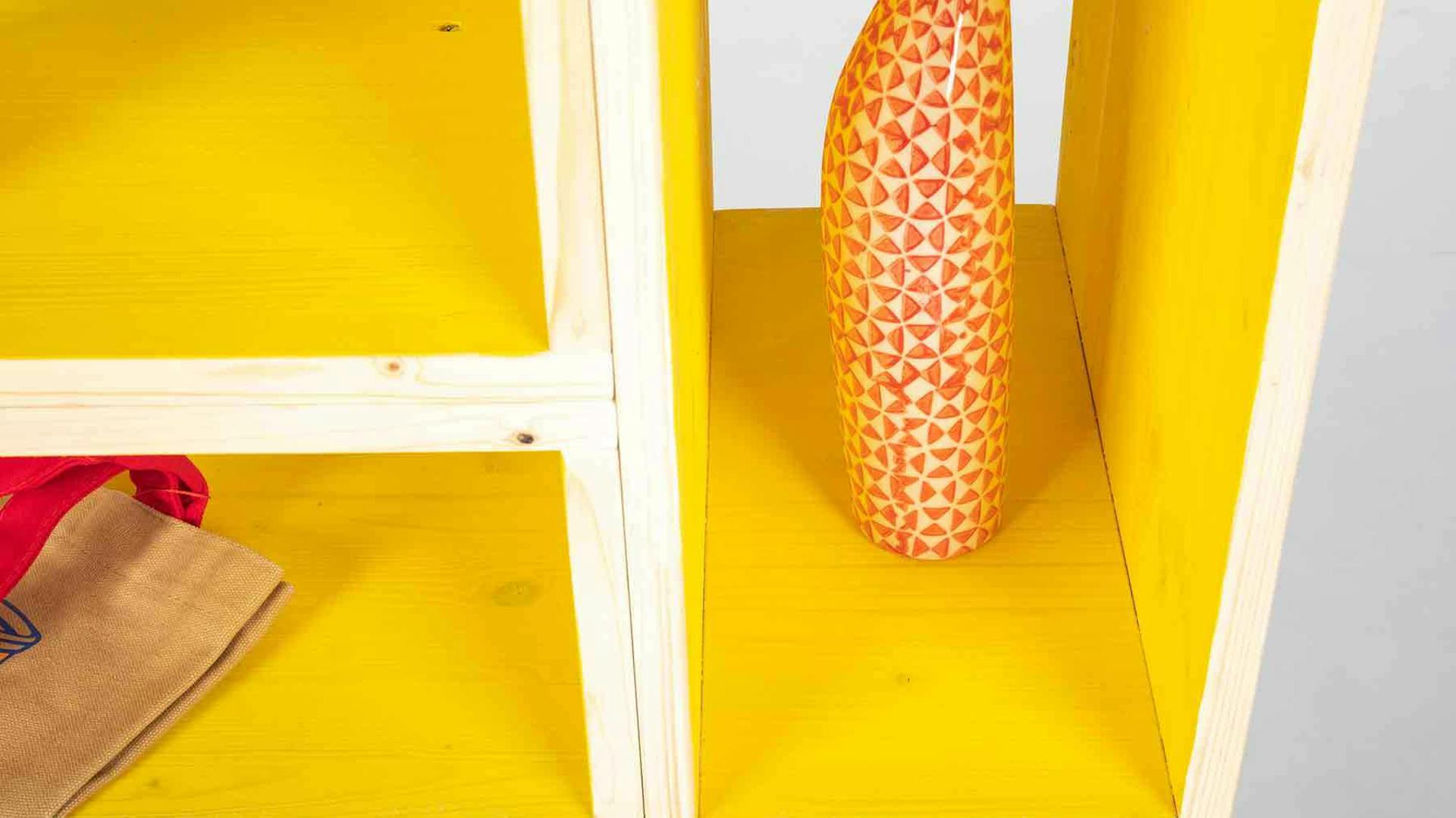 Regalfächer aus hellem Holz, deren Innenseite gelb lackiert ist