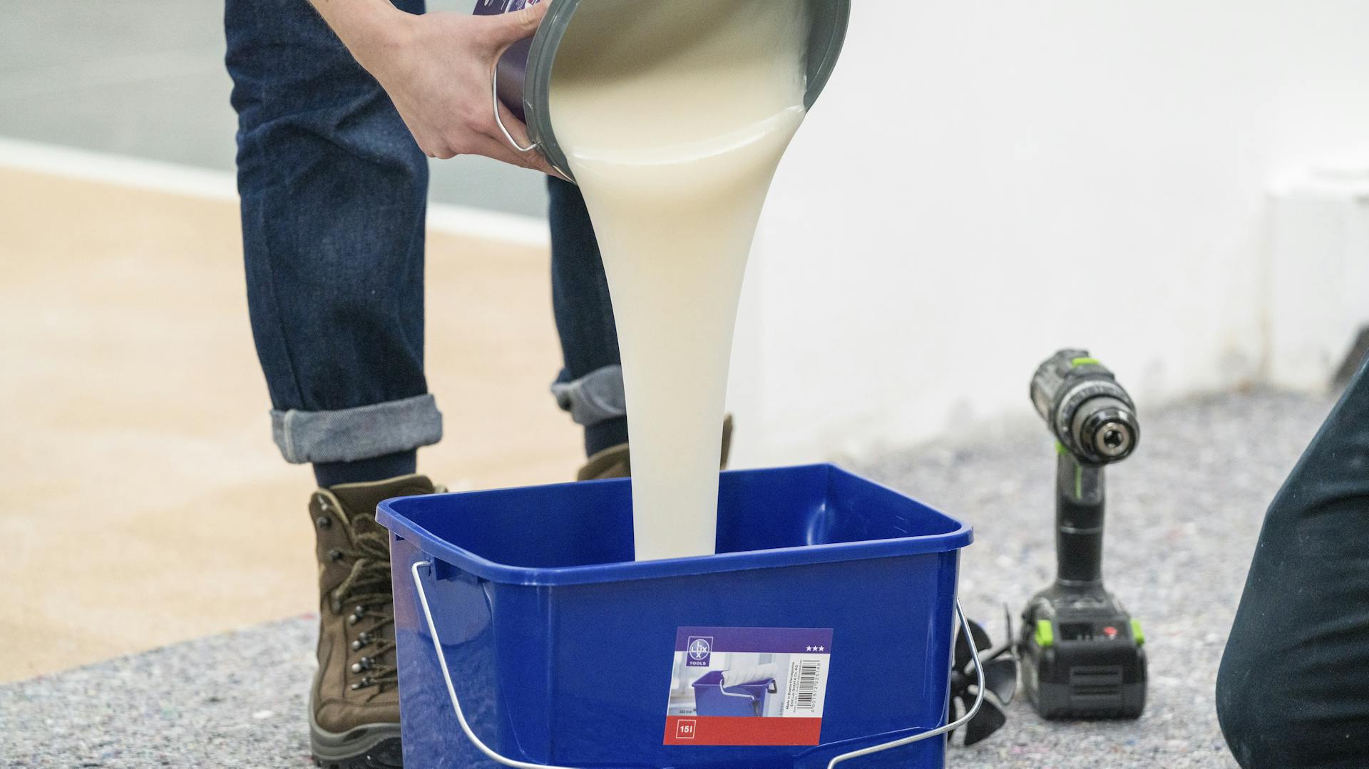 Person schüttet Kleister in Eimer.