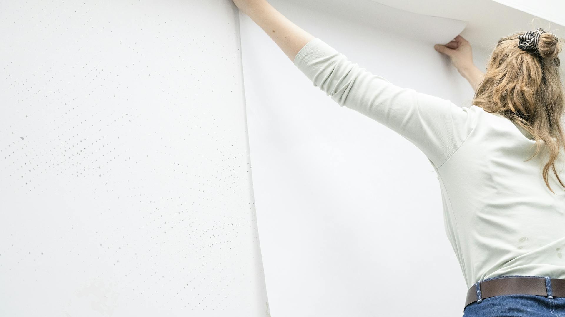 Eine Frau tapeziert Renoviervlies.