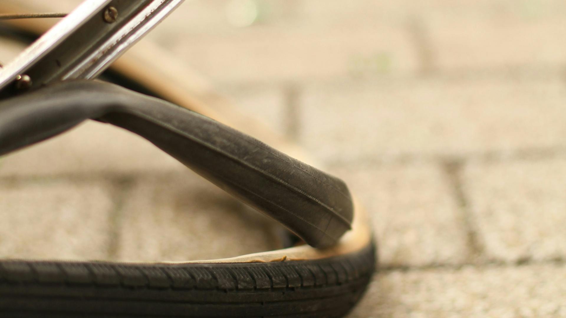 Rad von Fahrrad mit abgelöstem Schlauch und Reifen auf Pflastersteinen