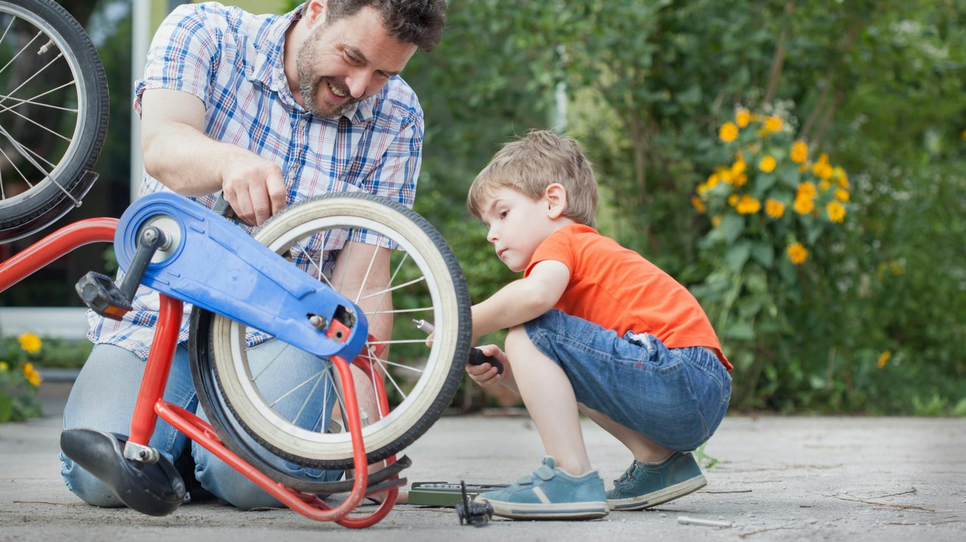 Vater und Sohn reparieren gemeinsam Kinderfahrrad
