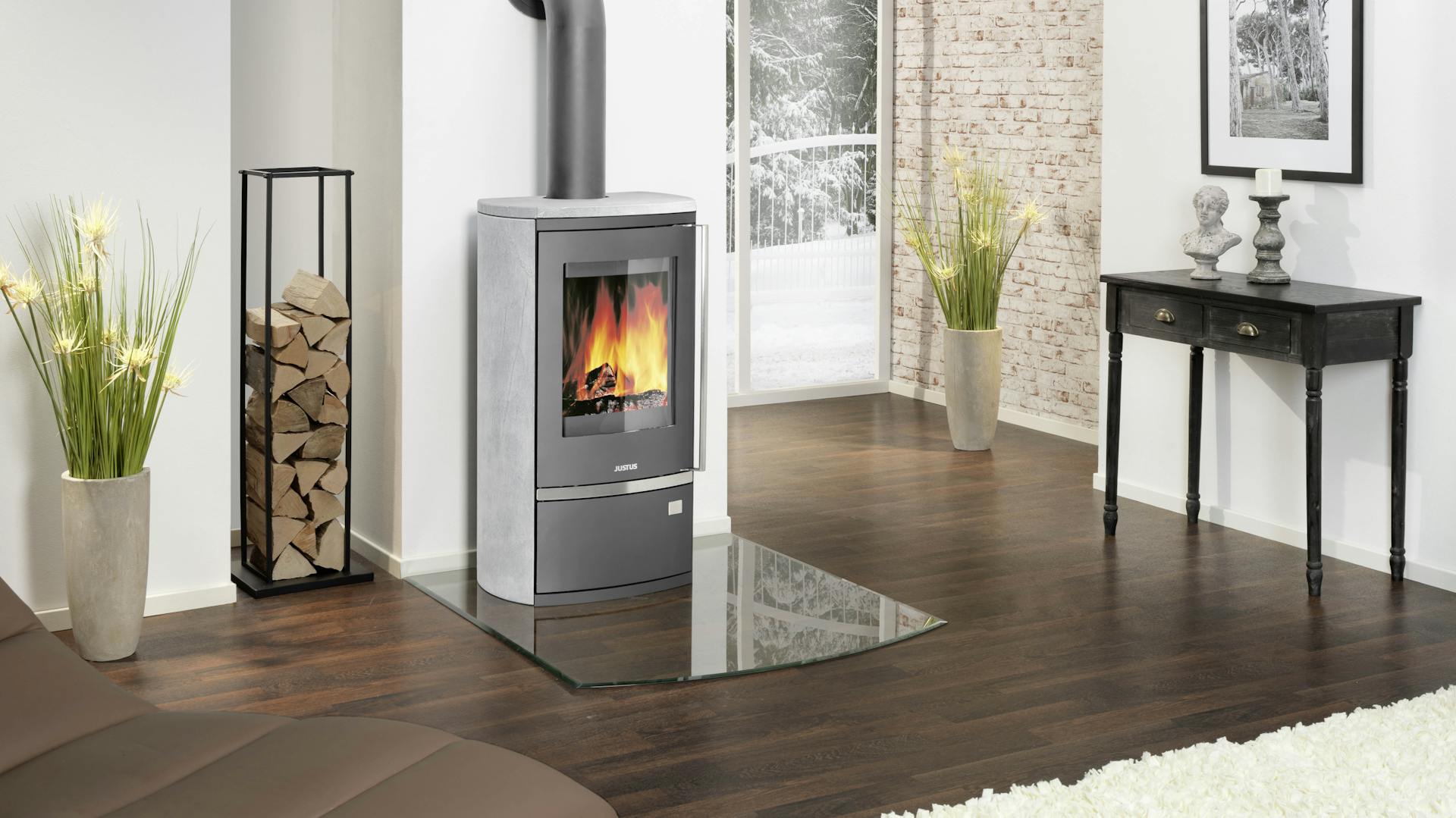 Ein grauer Dauerbrandofen aus Speckstein steht an der Wand in einem Flur mit dunklem Holzboden und hellen Wänden.