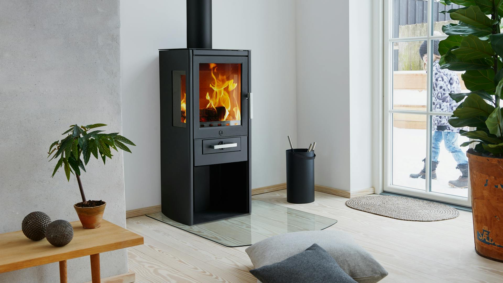 Una stufa caminetto nera a legna, accesa in un luminoso soggiorno.