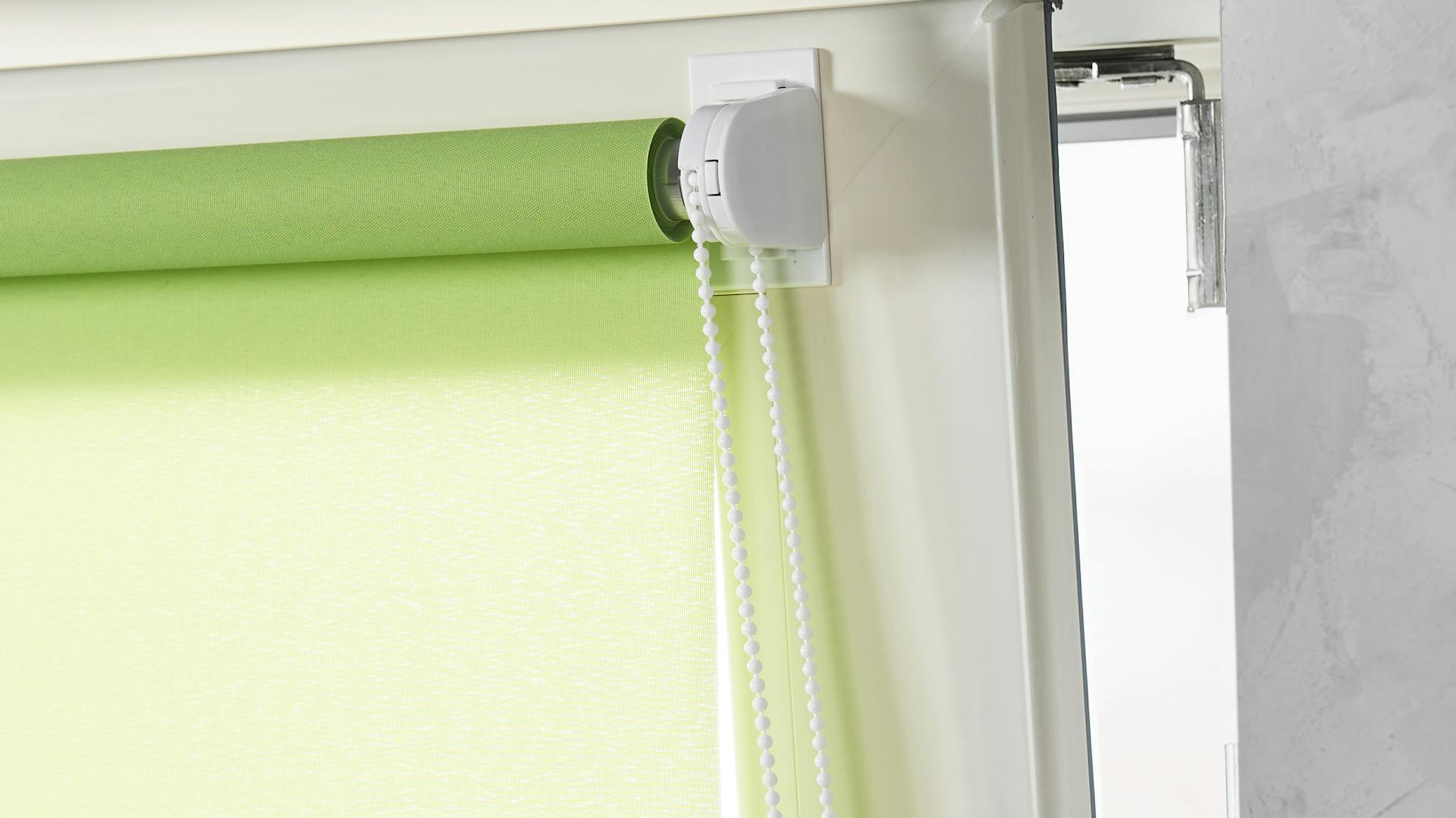 Ein grünes Rollo ist auf dem Fensterflügel eines Fensters angebracht.