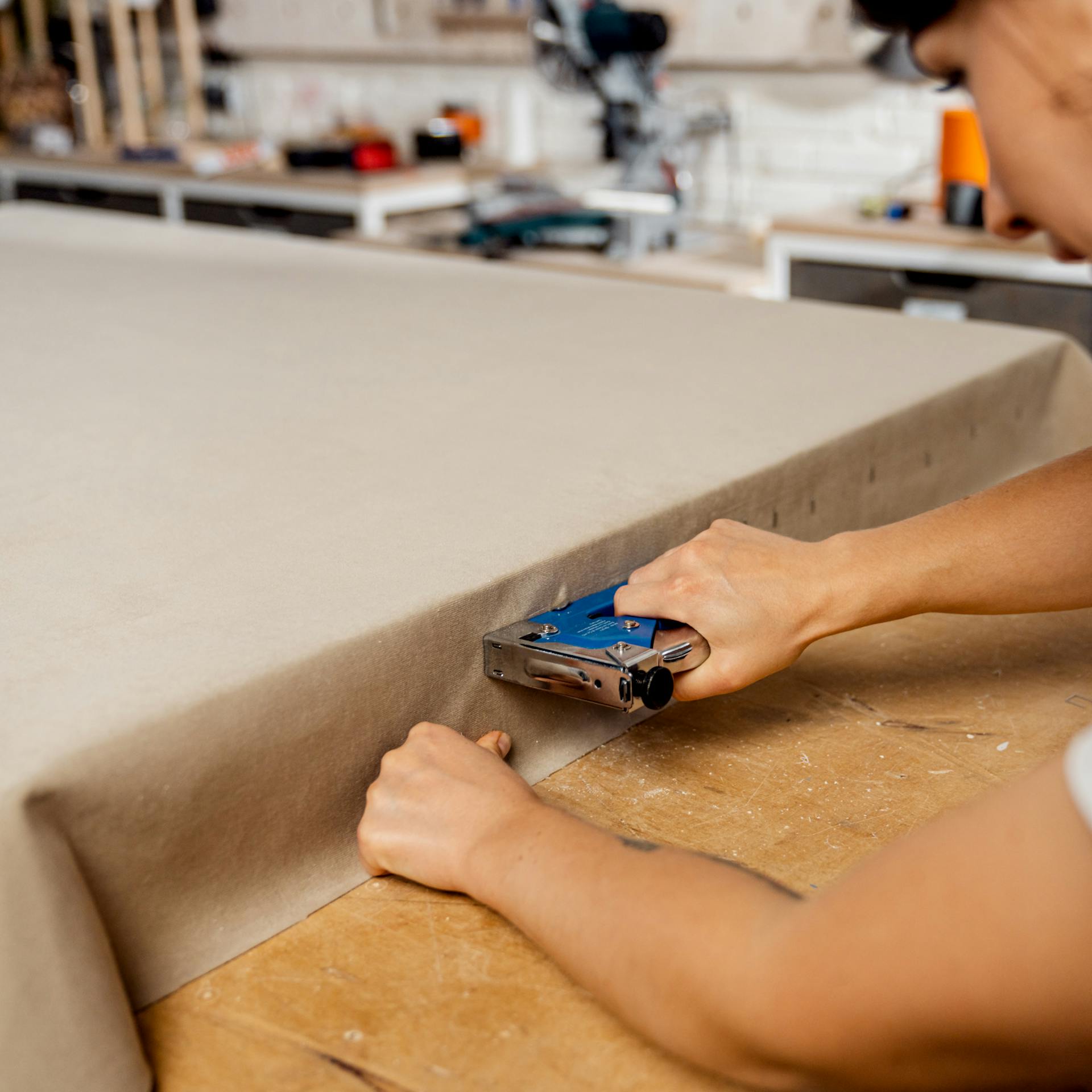 Schallabsorber wird mit Hilfe von Handtacker seitlich mit Stoff bespannt