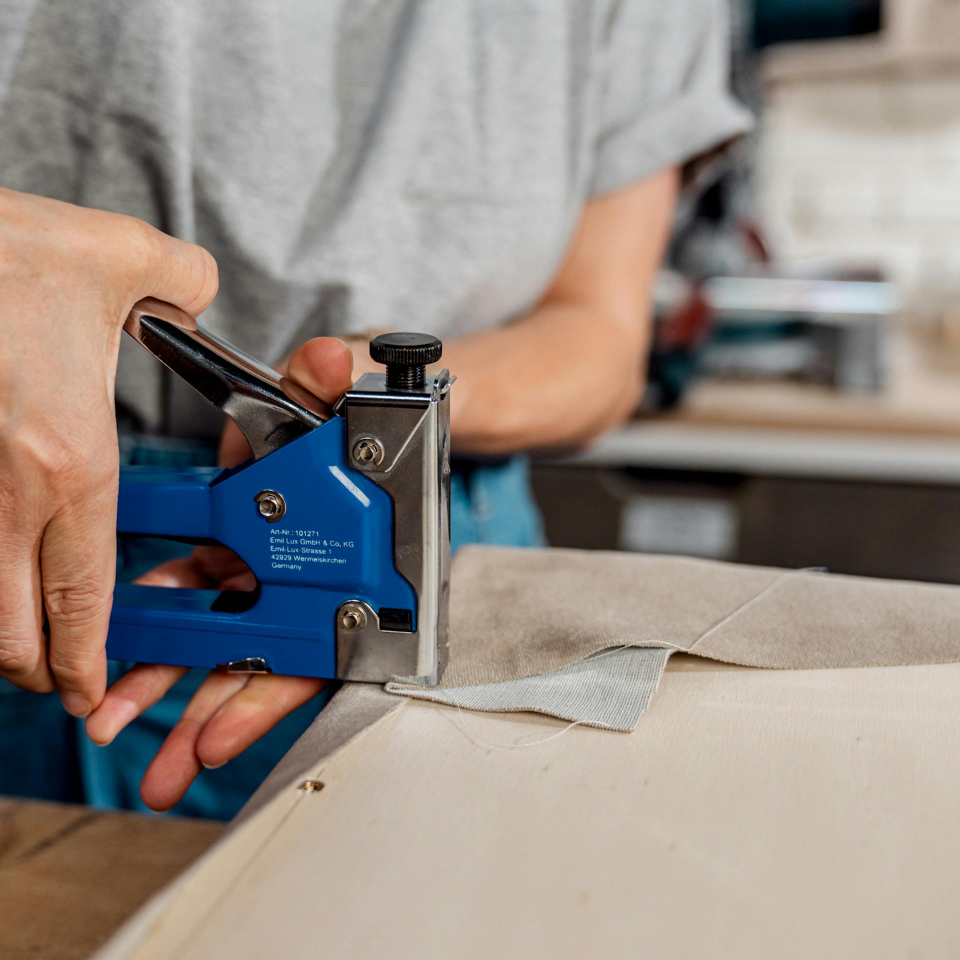 Schallabsorber wird mit Hilfe von Handtacker mit Stoff bespannt