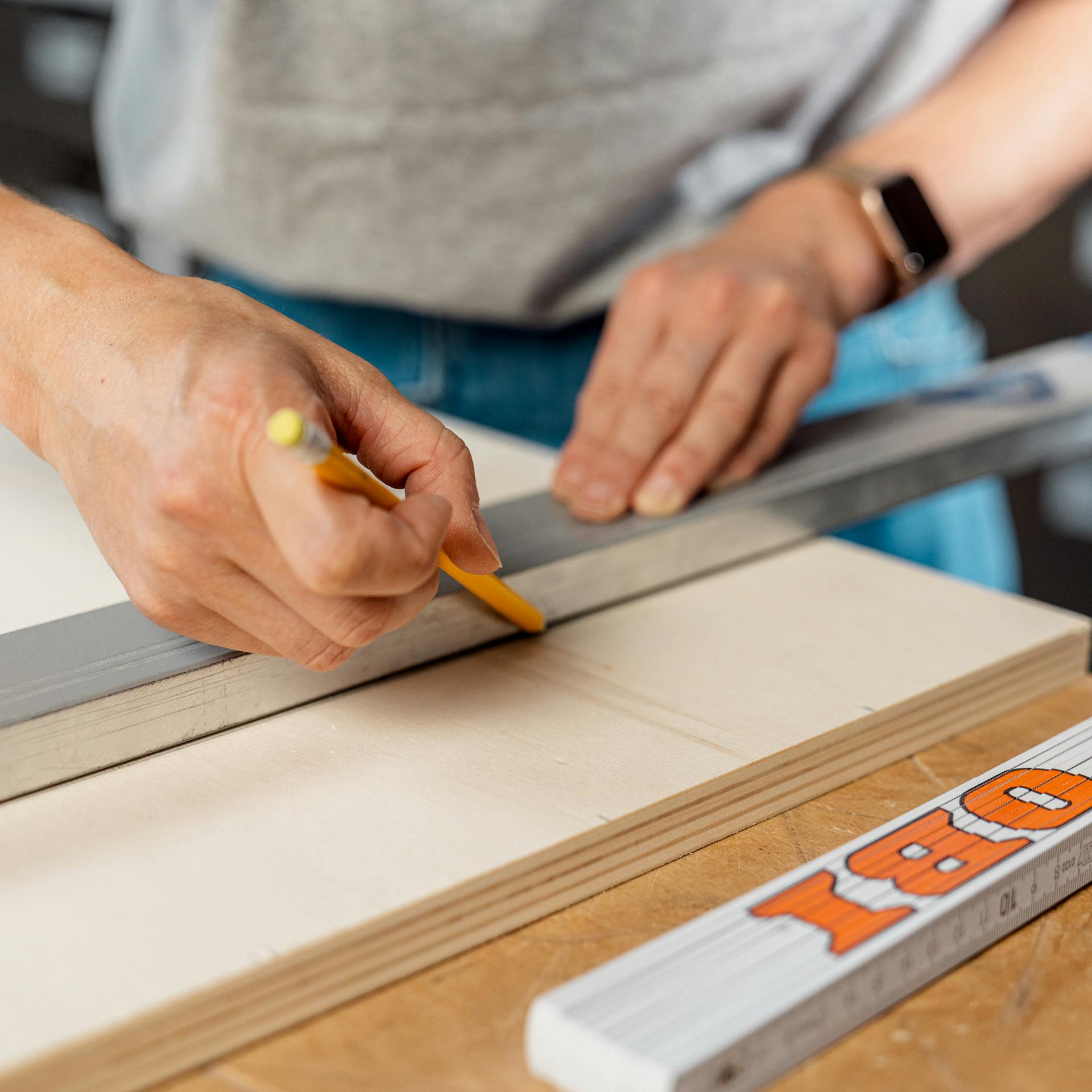Maße auf Holzplatte werden mit Bleistift und Lineal angezeichnet
