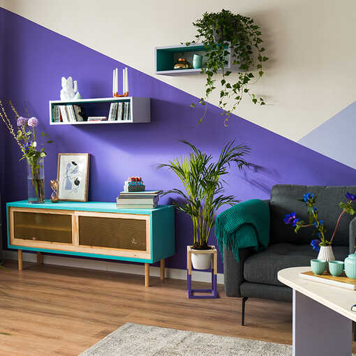 Sideboard Jona steht vor einer Wand, die eine große geometrische Formen in der Trendfarbe Blau-Lila als Wandgestaltung nutzt.] 