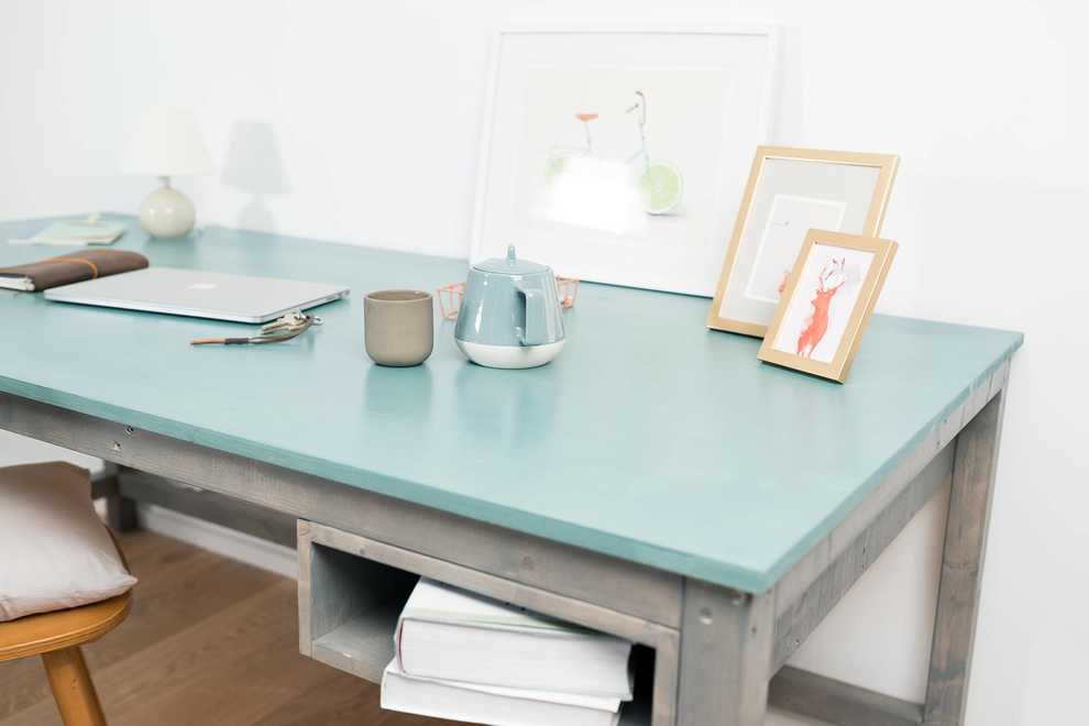 Auf Schreibtisch Egon mit hellblauer Platte und grauer Unterkonstruktion befinden sich Büromaterialien und Fotos