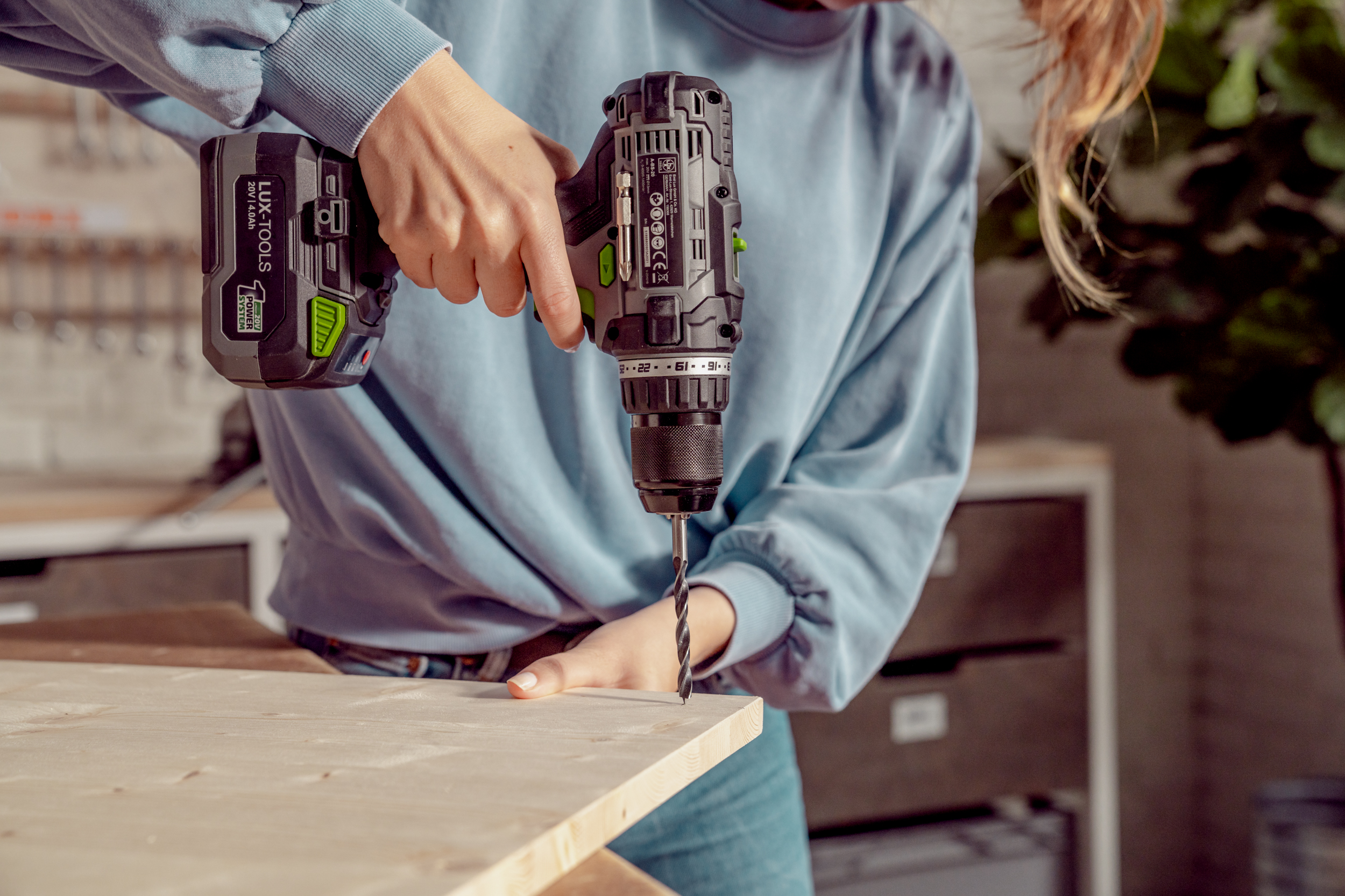Frau bohrt Löcher in die Holzplatte