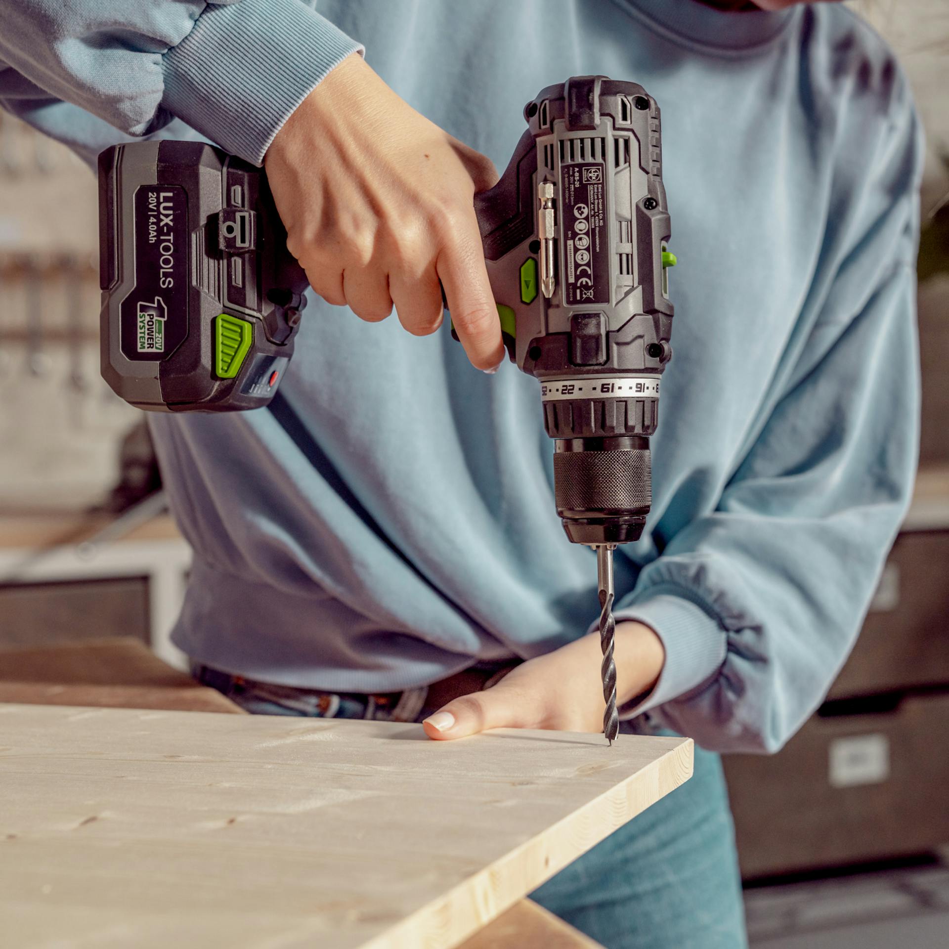 Frau bohrt Löcher in die Holzplatte