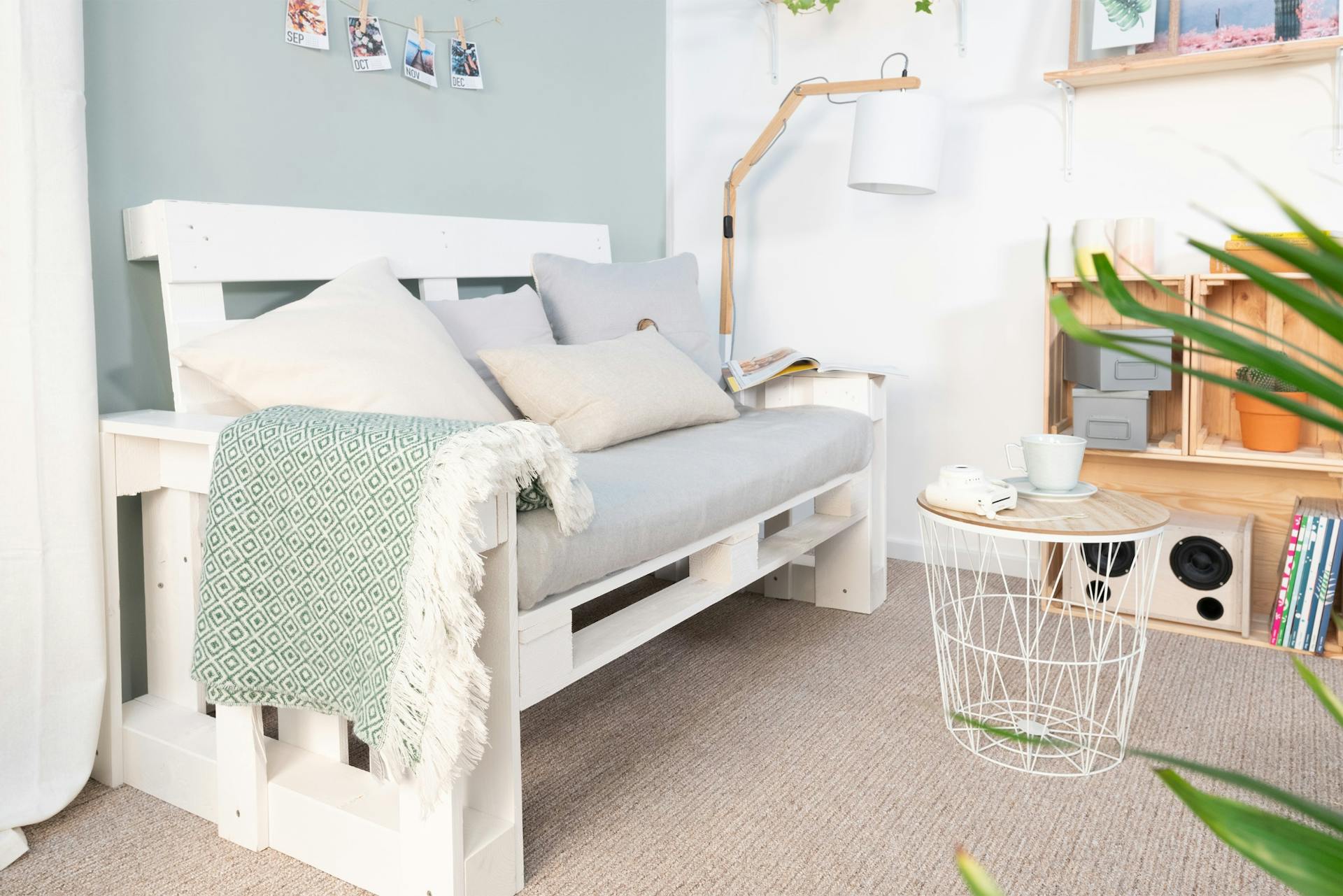Palettensofa mit Armlehnen in Wohnzimmer auf Teppich vor hellblauer Wand