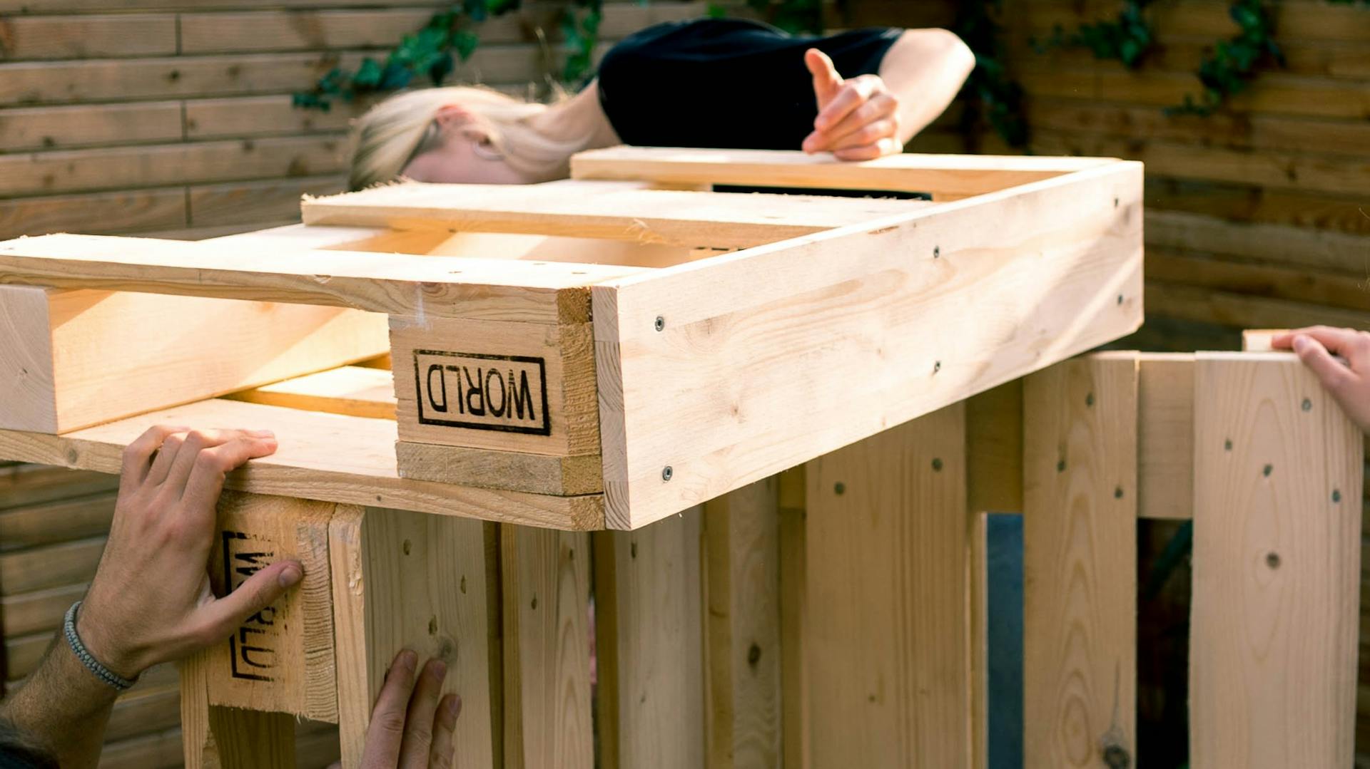 Heimwerker bringen Armlehne an Palettensofa an