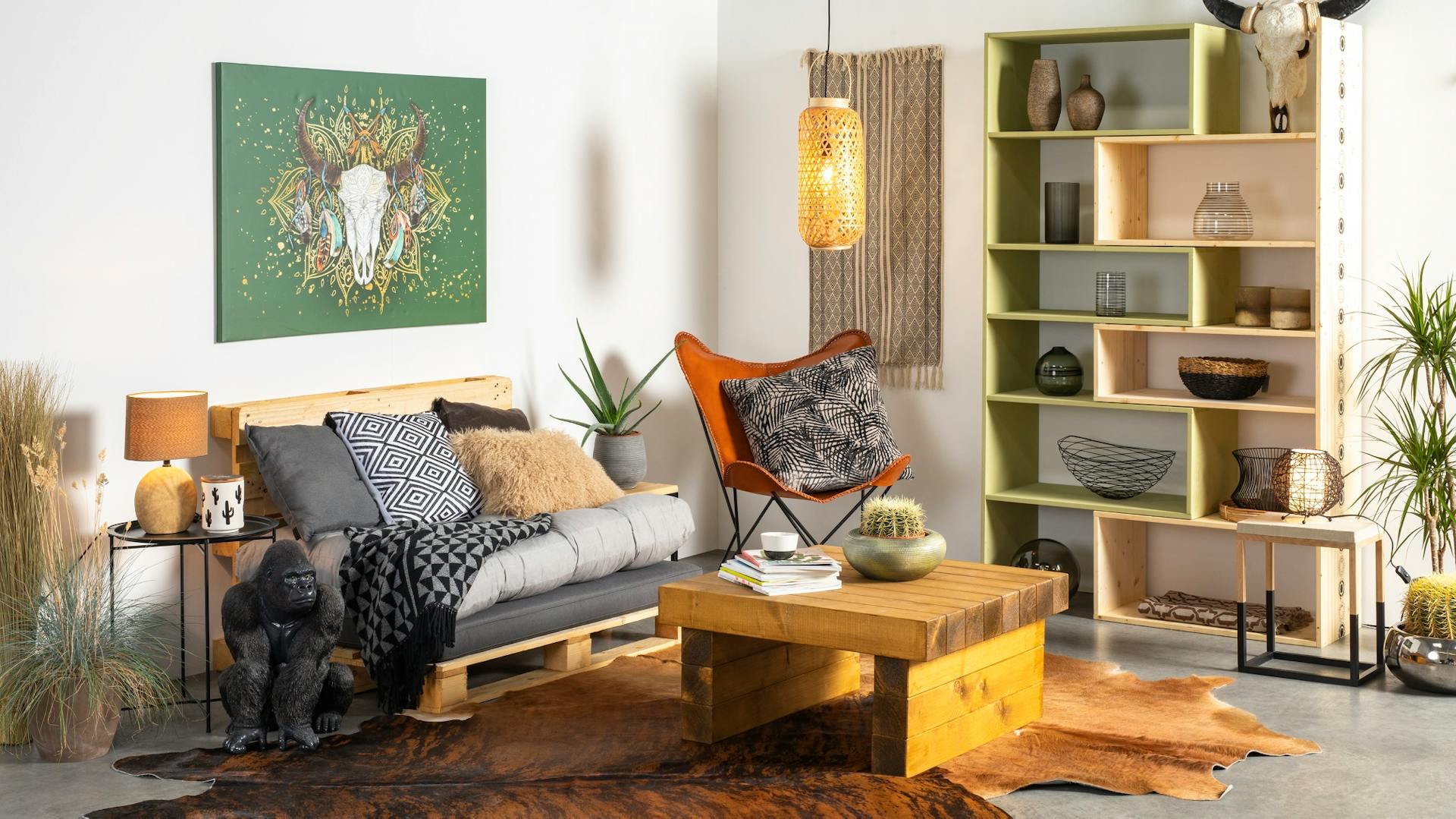 Palettensofa mit Auflage und Kissen in Wohnzimmer hinter Couchtisch neben Regal