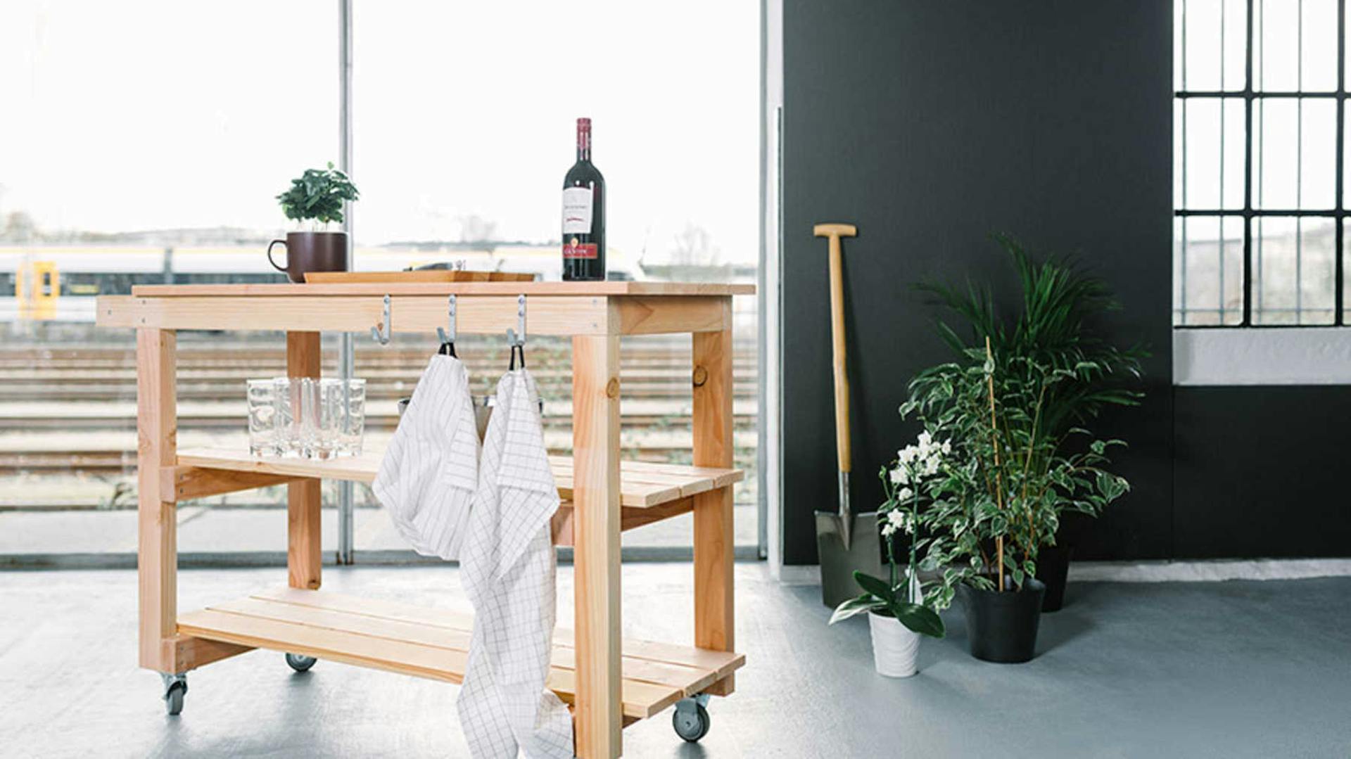 Auf Servierwagen Sophie ist Geschirr und Wein platziert. An den Haken des Wagens hängen Küchen-Handtücher.