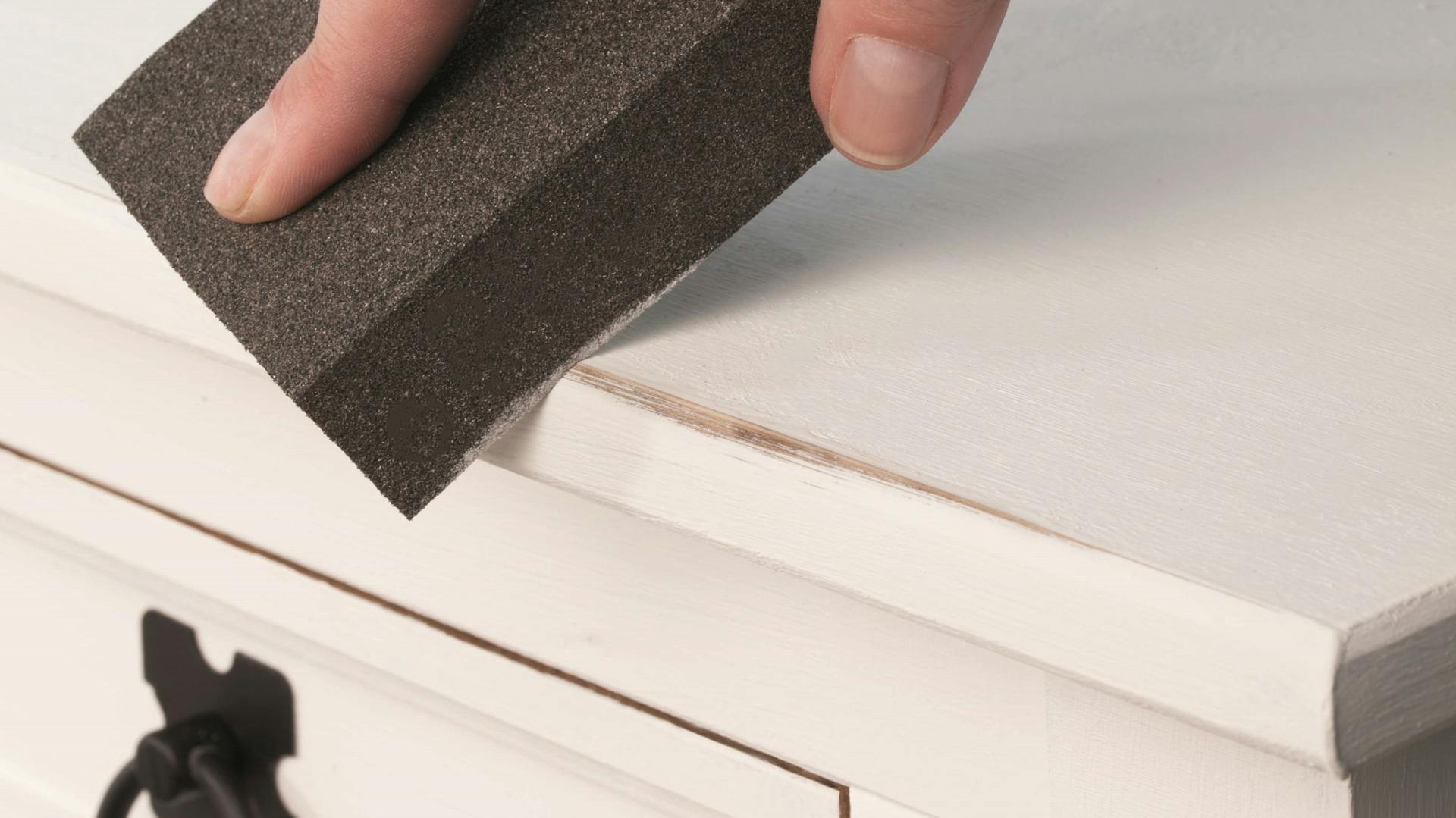 Altes Möbel wird nach Anstrich mit weißer Kreidefarbe für den Shabby-Look angeschliffen